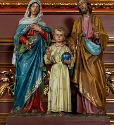 Zdjęcie nr 11: Ołtarz architektoniczny, jednoosiowy, jednokondygnacyjny ze zwieńczeniem. Retabulum osadzone jest na wysokim, zdwojonym, zryzalitowanym uskokowo cokole. Ołtarz jest prostopadłościenny z drewnianą mensą. Część środkową ujmuje para kolumn o żłobkowanych trzonach i korynckich kapitelach, ustawionych na tle zdwojonych pilastrów. Podpory dźwigają wyłamujące się ponad nimi belkowanie o silnie wysuniętym gzymsie. Zwieńczenie ma formę aediculi ujętej parą pilastrów i spływów wolutowych, zamkniętej trójkątnym przyczółkiem. Dodatkowo ujęta jest ona przerwanym, półkolistym przyczółkiem. Płycina antepedium jest w kształcie leżącego prostokąta z płaskorzeźbionym motywem złoconego kielicha eucharystycznego oraz kwiatów lilii skrzyżowanych z włócznią oraz trzciną z gąbką na tle srebrzonych obłoków ujętych promienistą glorią. Płyciny górnego cokołu (predelli) zdobi motyw ostów i cierni. Część środkową ujmuje para ażurowych, akantowych uszaków z motywem tuniki, kolumny biczowania oraz trzciny po lewej stronie i chusty św. Weroniki, drabiny, włóczni i trzciny z gąbką po prawej. U góry, pośrodku znajduje się uskrzydlona główka anielska. Powyżej, w partii belkowania, którego gzyms zdobi kostkowanie, jest umieszczony kartusz herbowy z monogramem IHS. Fryz zdobi stylizowana wić roślinna oraz para uskrzydlonych główek anielskich, natomiast zwieńczenie retabulum m.in. motywy roślinne, rozetki i kampanulle. Szczyt tworzy podtrzymująca krzyż para aniołów o sylwetkach od pasa w dół w formie liści akantu. Na przerwanym przyczółku znajduje się para przyklękających aniołów, ubranych w suknie w kolorach jasnoczerwonym i niebieskim oraz złocone płaszcze, trzymających w dłoniach włócznię i trzcinę z gąbką. Pole w części środkowej ma kształt stojącego prostokąta ujętego profilowaną, złoconą ramą. W środku znajduje się przedstawienie św. Anny nauczającej małą Marię. Pole w zwieńczeniu ma kształt stojącego owalu ujętego złoconą ramą w formie wieńca laurowego. Zawiera wizerunek św. Józefa. 
Struktura retabulum utrzymana jest w odcieniach brązu, partie detalu architektonicznego i ornamentyka są złocone.      
