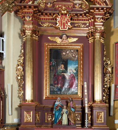 Zdjęcie nr 1: Ołtarz architektoniczny, jednoosiowy, jednokondygnacyjny ze zwieńczeniem. Retabulum osadzone jest na wysokim, zdwojonym, zryzalitowanym uskokowo cokole. Ołtarz jest prostopadłościenny z drewnianą mensą. Część środkową ujmuje para kolumn o żłobkowanych trzonach i korynckich kapitelach, ustawionych na tle zdwojonych pilastrów. Podpory dźwigają wyłamujące się ponad nimi belkowanie o silnie wysuniętym gzymsie. Zwieńczenie ma formę aediculi ujętej parą pilastrów i spływów wolutowych, zamkniętej trójkątnym przyczółkiem. Dodatkowo ujęta jest ona przerwanym, półkolistym przyczółkiem. Płycina antepedium jest w kształcie leżącego prostokąta z płaskorzeźbionym motywem złoconego kielicha eucharystycznego oraz kwiatów lilii skrzyżowanych z włócznią oraz trzciną z gąbką na tle srebrzonych obłoków ujętych promienistą glorią. Płyciny górnego cokołu (predelli) zdobi motyw ostów i cierni. Część środkową ujmuje para ażurowych, akantowych uszaków z motywem tuniki, kolumny biczowania oraz trzciny po lewej stronie i chusty św. Weroniki, drabiny, włóczni i trzciny z gąbką po prawej. U góry, pośrodku znajduje się uskrzydlona główka anielska. Powyżej, w partii belkowania, którego gzyms zdobi kostkowanie, jest umieszczony kartusz herbowy z monogramem IHS. Fryz zdobi stylizowana wić roślinna oraz para uskrzydlonych główek anielskich, natomiast zwieńczenie retabulum m.in. motywy roślinne, rozetki i kampanulle. Szczyt tworzy podtrzymująca krzyż para aniołów o sylwetkach od pasa w dół w formie liści akantu. Na przerwanym przyczółku znajduje się para przyklękających aniołów, ubranych w suknie w kolorach jasnoczerwonym i niebieskim oraz złocone płaszcze, trzymających w dłoniach włócznię i trzcinę z gąbką. Pole w części środkowej ma kształt stojącego prostokąta ujętego profilowaną, złoconą ramą. W środku znajduje się przedstawienie św. Anny nauczającej małą Marię. Pole w zwieńczeniu ma kształt stojącego owalu ujętego złoconą ramą w formie wieńca laurowego. Zawiera wizerunek św. Józefa. 
Struktura retabulum utrzymana jest w odcieniach brązu, partie detalu architektonicznego i ornamentyka są złocone.      
