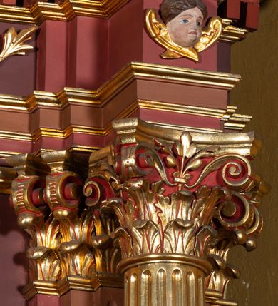 Zdjęcie nr 13: Ołtarz architektoniczny, jednoosiowy, jednokondygnacyjny ze zwieńczeniem. Retabulum osadzone jest na wysokim, zdwojonym, zryzalitowanym uskokowo cokole. Ołtarz jest prostopadłościenny z drewnianą mensą. Część środkową ujmuje para kolumn o żłobkowanych trzonach i korynckich kapitelach, ustawionych na tle zdwojonych pilastrów. Podpory dźwigają wyłamujące się ponad nimi belkowanie o silnie wysuniętym gzymsie. Zwieńczenie ma formę aediculi ujętej parą pilastrów i spływów wolutowych, zamkniętej trójkątnym przyczółkiem. Dodatkowo ujęta jest ona przerwanym, półkolistym przyczółkiem. Płycina antepedium jest w kształcie leżącego prostokąta z płaskorzeźbionym motywem złoconego kielicha eucharystycznego oraz kwiatów lilii skrzyżowanych z włócznią oraz trzciną z gąbką na tle srebrzonych obłoków ujętych promienistą glorią. Płyciny górnego cokołu (predelli) zdobi motyw ostów i cierni. Część środkową ujmuje para ażurowych, akantowych uszaków z motywem tuniki, kolumny biczowania oraz trzciny po lewej stronie i chusty św. Weroniki, drabiny, włóczni i trzciny z gąbką po prawej. U góry, pośrodku znajduje się uskrzydlona główka anielska. Powyżej, w partii belkowania, którego gzyms zdobi kostkowanie, jest umieszczony kartusz herbowy z monogramem IHS. Fryz zdobi stylizowana wić roślinna oraz para uskrzydlonych główek anielskich, natomiast zwieńczenie retabulum m.in. motywy roślinne, rozetki i kampanulle. Szczyt tworzy podtrzymująca krzyż para aniołów o sylwetkach od pasa w dół w formie liści akantu. Na przerwanym przyczółku znajduje się para przyklękających aniołów, ubranych w suknie w kolorach jasnoczerwonym i niebieskim oraz złocone płaszcze, trzymających w dłoniach włócznię i trzcinę z gąbką. Pole w części środkowej ma kształt stojącego prostokąta ujętego profilowaną, złoconą ramą. W środku znajduje się przedstawienie św. Anny nauczającej małą Marię. Pole w zwieńczeniu ma kształt stojącego owalu ujętego złoconą ramą w formie wieńca laurowego. Zawiera wizerunek św. Józefa. 
Struktura retabulum utrzymana jest w odcieniach brązu, partie detalu architektonicznego i ornamentyka są złocone.      
