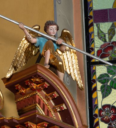 Zdjęcie nr 9: Ołtarz architektoniczny, jednoosiowy, jednokondygnacyjny ze zwieńczeniem. Retabulum osadzone jest na wysokim, zdwojonym, zryzalitowanym uskokowo cokole. Ołtarz jest prostopadłościenny z drewnianą mensą. Część środkową ujmuje para kolumn o żłobkowanych trzonach i korynckich kapitelach, ustawionych na tle zdwojonych pilastrów. Podpory dźwigają wyłamujące się ponad nimi belkowanie o silnie wysuniętym gzymsie. Zwieńczenie ma formę aediculi ujętej parą pilastrów i spływów wolutowych, zamkniętej trójkątnym przyczółkiem. Dodatkowo ujęta jest ona przerwanym, półkolistym przyczółkiem. Płycina antepedium jest w kształcie leżącego prostokąta z płaskorzeźbionym motywem złoconego kielicha eucharystycznego oraz kwiatów lilii skrzyżowanych z włócznią oraz trzciną z gąbką na tle srebrzonych obłoków ujętych promienistą glorią. Płyciny górnego cokołu (predelli) zdobi motyw ostów i cierni. Część środkową ujmuje para ażurowych, akantowych uszaków z motywem tuniki, kolumny biczowania oraz trzciny po lewej stronie i chusty św. Weroniki, drabiny, włóczni i trzciny z gąbką po prawej. U góry, pośrodku znajduje się uskrzydlona główka anielska. Powyżej, w partii belkowania, którego gzyms zdobi kostkowanie, jest umieszczony kartusz herbowy z monogramem IHS. Fryz zdobi stylizowana wić roślinna oraz para uskrzydlonych główek anielskich, natomiast zwieńczenie retabulum m.in. motywy roślinne, rozetki i kampanulle. Szczyt tworzy podtrzymująca krzyż para aniołów o sylwetkach od pasa w dół w formie liści akantu. Na przerwanym przyczółku znajduje się para przyklękających aniołów, ubranych w suknie w kolorach jasnoczerwonym i niebieskim oraz złocone płaszcze, trzymających w dłoniach włócznię i trzcinę z gąbką. Pole w części środkowej ma kształt stojącego prostokąta ujętego profilowaną, złoconą ramą. W środku znajduje się przedstawienie św. Anny nauczającej małą Marię. Pole w zwieńczeniu ma kształt stojącego owalu ujętego złoconą ramą w formie wieńca laurowego. Zawiera wizerunek św. Józefa. 
Struktura retabulum utrzymana jest w odcieniach brązu, partie detalu architektonicznego i ornamentyka są złocone.      
