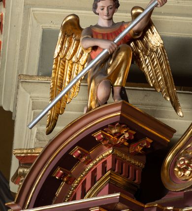 Zdjęcie nr 7: Ołtarz architektoniczny, jednoosiowy, jednokondygnacyjny ze zwieńczeniem. Retabulum osadzone jest na wysokim, zdwojonym, zryzalitowanym uskokowo cokole. Ołtarz jest prostopadłościenny z drewnianą mensą. Część środkową ujmuje para kolumn o żłobkowanych trzonach i korynckich kapitelach, ustawionych na tle zdwojonych pilastrów. Podpory dźwigają wyłamujące się ponad nimi belkowanie o silnie wysuniętym gzymsie. Zwieńczenie ma formę aediculi ujętej parą pilastrów i spływów wolutowych, zamkniętej trójkątnym przyczółkiem. Dodatkowo ujęta jest ona przerwanym, półkolistym przyczółkiem. Płycina antepedium jest w kształcie leżącego prostokąta z płaskorzeźbionym motywem złoconego kielicha eucharystycznego oraz kwiatów lilii skrzyżowanych z włócznią oraz trzciną z gąbką na tle srebrzonych obłoków ujętych promienistą glorią. Płyciny górnego cokołu (predelli) zdobi motyw ostów i cierni. Część środkową ujmuje para ażurowych, akantowych uszaków z motywem tuniki, kolumny biczowania oraz trzciny po lewej stronie i chusty św. Weroniki, drabiny, włóczni i trzciny z gąbką po prawej. U góry, pośrodku znajduje się uskrzydlona główka anielska. Powyżej, w partii belkowania, którego gzyms zdobi kostkowanie, jest umieszczony kartusz herbowy z monogramem IHS. Fryz zdobi stylizowana wić roślinna oraz para uskrzydlonych główek anielskich, natomiast zwieńczenie retabulum m.in. motywy roślinne, rozetki i kampanulle. Szczyt tworzy podtrzymująca krzyż para aniołów o sylwetkach od pasa w dół w formie liści akantu. Na przerwanym przyczółku znajduje się para przyklękających aniołów, ubranych w suknie w kolorach jasnoczerwonym i niebieskim oraz złocone płaszcze, trzymających w dłoniach włócznię i trzcinę z gąbką. Pole w części środkowej ma kształt stojącego prostokąta ujętego profilowaną, złoconą ramą. W środku znajduje się przedstawienie św. Anny nauczającej małą Marię. Pole w zwieńczeniu ma kształt stojącego owalu ujętego złoconą ramą w formie wieńca laurowego. Zawiera wizerunek św. Józefa. 
Struktura retabulum utrzymana jest w odcieniach brązu, partie detalu architektonicznego i ornamentyka są złocone.      
