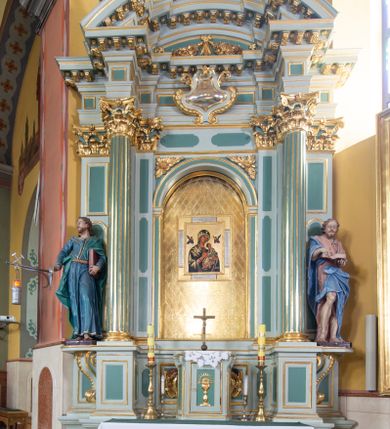 Zdjęcie nr 1: Ołtarz przyścienny, prostopadłościenny, z antepedium, na którym umieszczony jest rzeźbiony monogram Marii; mensa drewniana z kamiennym portatylem. Na mensie znajduje się tabernakulum o kształcie graniastosłupa, z drzwiczkami ozdobionymi rzeźbionym kielichem z hostią. Nastawa ołtarzowa jest architektoniczna, jednoosiowa, jednokondygnacyjna ze zwieńczeniem. Osadzona na podwójnym postumencie, flankowana pilastrami o kompozytowych kapitelach i kanelowanymi kolumnami o kompozytowych kapitelach, które podtrzymują belkowanie. Ponad belkowaniem znajduje się przełamany przyczółek w formie łuku półkolistego, bogato profilowany, ozdobiony ulistnionymi konsolkami i rozetami oraz girlandami z owoców. W partii fryzu kartusz o fantazyjnym wykroju, ujęty wolutami i listkami akantu. Na belkowaniu siedzą po bokach putta, odziane tkaniną na biodrach, a pośrodku znajduje się krzyż osadzony na postumencie z liśćmi. Po obu stronach ołtarza na konsolach o krawędziach ozdobionych ornamentem małżowinowym stoją figury trudnych do identyfikacji świętych, być może apostołów. W centralnej części ołtarza wnęka prostokątna, zamknięta łukiem półkolistym, wypełniona złoconą blachą z rytą ukośną kratką wypełnioną rozetkami. Na blasze zawieszony obraz z przedstawieniem Matki Boskiej Nieustającej Pomocy, który ujęty jest w prostokątną, blaszaną ramę. 

