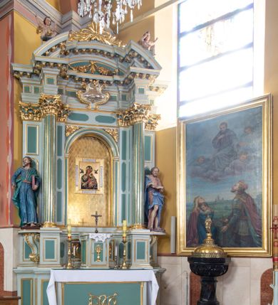 Zdjęcie nr 2: Ołtarz przyścienny, prostopadłościenny, z antepedium, na którym umieszczony jest rzeźbiony monogram Marii; mensa drewniana z kamiennym portatylem. Na mensie znajduje się tabernakulum o kształcie graniastosłupa, z drzwiczkami ozdobionymi rzeźbionym kielichem z hostią. Nastawa ołtarzowa jest architektoniczna, jednoosiowa, jednokondygnacyjna ze zwieńczeniem. Osadzona na podwójnym postumencie, flankowana pilastrami o kompozytowych kapitelach i kanelowanymi kolumnami o kompozytowych kapitelach, które podtrzymują belkowanie. Ponad belkowaniem znajduje się przełamany przyczółek w formie łuku półkolistego, bogato profilowany, ozdobiony ulistnionymi konsolkami i rozetami oraz girlandami z owoców. W partii fryzu kartusz o fantazyjnym wykroju, ujęty wolutami i listkami akantu. Na belkowaniu siedzą po bokach putta, odziane tkaniną na biodrach, a pośrodku znajduje się krzyż osadzony na postumencie z liśćmi. Po obu stronach ołtarza na konsolach o krawędziach ozdobionych ornamentem małżowinowym stoją figury trudnych do identyfikacji świętych, być może apostołów. W centralnej części ołtarza wnęka prostokątna, zamknięta łukiem półkolistym, wypełniona złoconą blachą z rytą ukośną kratką wypełnioną rozetkami. Na blasze zawieszony obraz z przedstawieniem Matki Boskiej Nieustającej Pomocy, który ujęty jest w prostokątną, blaszaną ramę. 

