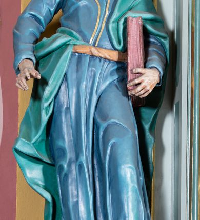 Zdjęcie nr 25: Ołtarz przyścienny, prostopadłościenny, z antepedium, na którym umieszczony jest rzeźbiony monogram Marii; mensa drewniana z kamiennym portatylem. Na mensie znajduje się tabernakulum o kształcie graniastosłupa, z drzwiczkami ozdobionymi rzeźbionym kielichem z hostią. Nastawa ołtarzowa jest architektoniczna, jednoosiowa, jednokondygnacyjna ze zwieńczeniem. Osadzona na podwójnym postumencie, flankowana pilastrami o kompozytowych kapitelach i kanelowanymi kolumnami o kompozytowych kapitelach, które podtrzymują belkowanie. Ponad belkowaniem znajduje się przełamany przyczółek w formie łuku półkolistego, bogato profilowany, ozdobiony ulistnionymi konsolkami i rozetami oraz girlandami z owoców. W partii fryzu kartusz o fantazyjnym wykroju, ujęty wolutami i listkami akantu. Na belkowaniu siedzą po bokach putta, odziane tkaniną na biodrach, a pośrodku znajduje się krzyż osadzony na postumencie z liśćmi. Po obu stronach ołtarza na konsolach o krawędziach ozdobionych ornamentem małżowinowym stoją figury trudnych do identyfikacji świętych, być może apostołów. W centralnej części ołtarza wnęka prostokątna, zamknięta łukiem półkolistym, wypełniona złoconą blachą z rytą ukośną kratką wypełnioną rozetkami. Na blasze zawieszony obraz z przedstawieniem Matki Boskiej Nieustającej Pomocy, który ujęty jest w prostokątną, blaszaną ramę. 

