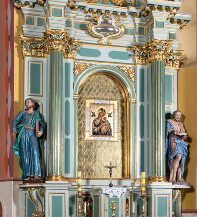 Zdjęcie nr 20: Ołtarz przyścienny, prostopadłościenny, z antepedium, na którym umieszczony jest rzeźbiony monogram Marii; mensa drewniana z kamiennym portatylem. Na mensie znajduje się tabernakulum o kształcie graniastosłupa, z drzwiczkami ozdobionymi rzeźbionym kielichem z hostią. Nastawa ołtarzowa jest architektoniczna, jednoosiowa, jednokondygnacyjna ze zwieńczeniem. Osadzona na podwójnym postumencie, flankowana pilastrami o kompozytowych kapitelach i kanelowanymi kolumnami o kompozytowych kapitelach, które podtrzymują belkowanie. Ponad belkowaniem znajduje się przełamany przyczółek w formie łuku półkolistego, bogato profilowany, ozdobiony ulistnionymi konsolkami i rozetami oraz girlandami z owoców. W partii fryzu kartusz o fantazyjnym wykroju, ujęty wolutami i listkami akantu. Na belkowaniu siedzą po bokach putta, odziane tkaniną na biodrach, a pośrodku znajduje się krzyż osadzony na postumencie z liśćmi. Po obu stronach ołtarza na konsolach o krawędziach ozdobionych ornamentem małżowinowym stoją figury trudnych do identyfikacji świętych, być może apostołów. W centralnej części ołtarza wnęka prostokątna, zamknięta łukiem półkolistym, wypełniona złoconą blachą z rytą ukośną kratką wypełnioną rozetkami. Na blasze zawieszony obraz z przedstawieniem Matki Boskiej Nieustającej Pomocy, który ujęty jest w prostokątną, blaszaną ramę. 

