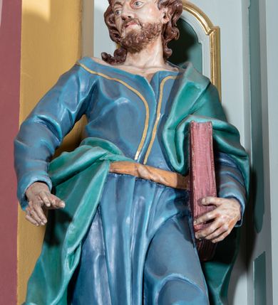 Zdjęcie nr 7: Ołtarz przyścienny, prostopadłościenny, z antepedium, na którym umieszczony jest rzeźbiony monogram Marii; mensa drewniana z kamiennym portatylem. Na mensie znajduje się tabernakulum o kształcie graniastosłupa, z drzwiczkami ozdobionymi rzeźbionym kielichem z hostią. Nastawa ołtarzowa jest architektoniczna, jednoosiowa, jednokondygnacyjna ze zwieńczeniem. Osadzona na podwójnym postumencie, flankowana pilastrami o kompozytowych kapitelach i kanelowanymi kolumnami o kompozytowych kapitelach, które podtrzymują belkowanie. Ponad belkowaniem znajduje się przełamany przyczółek w formie łuku półkolistego, bogato profilowany, ozdobiony ulistnionymi konsolkami i rozetami oraz girlandami z owoców. W partii fryzu kartusz o fantazyjnym wykroju, ujęty wolutami i listkami akantu. Na belkowaniu siedzą po bokach putta, odziane tkaniną na biodrach, a pośrodku znajduje się krzyż osadzony na postumencie z liśćmi. Po obu stronach ołtarza na konsolach o krawędziach ozdobionych ornamentem małżowinowym stoją figury trudnych do identyfikacji świętych, być może apostołów. W centralnej części ołtarza wnęka prostokątna, zamknięta łukiem półkolistym, wypełniona złoconą blachą z rytą ukośną kratką wypełnioną rozetkami. Na blasze zawieszony obraz z przedstawieniem Matki Boskiej Nieustającej Pomocy, który ujęty jest w prostokątną, blaszaną ramę. 

