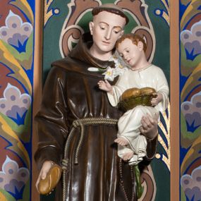 Zdjęcie nr 1: Rzeźba pełna, ustawiona na niskiej, profilowanej podstawie. Święty ukazany frontalnie, z ugiętą lewą nogą, pochyloną głową, w prawej opuszczonej w dół ręce trzyma bochenek chleba, lewą podtrzymuje Dzieciątko i przytrzymuje gałązkę lilii. Twarz ma szczupłą, o migdałowatych oczach skierowanych w dół, prostym, wąskim nosie i ustach. Włosy ma krótkie, brązowe, na głowie tonsura. Ubrany jest w ciemnobrązowy habit z kapturem, przewiązany w pasie podwójnym sznurem. Przy lewym boku ma zawieszony różaniec. Dzieciątko w pozycji siedzącej, z pochyloną głową, prawą rączkę unosi w geście błogosławieństwa, lewą przytrzymuje leżący na jego kolanach koszyk z bochenkami chleba. Twarz ma szczupłą, o wąskich oczach, małym nosie i ustach; okoloną krótkimi, brązowymi włosami. Ubrane jest w białą, luźną tunikę ze złoconą lamówką. Polichromia ciała figur naturalistyczna. 

