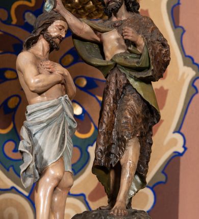 Zdjęcie nr 3: Chrzcielnica na rzucie ośmioboku, trzon i czara również są ośmioboczne. Cokół dwustopniowy, stopnie oddzielone od siebie zaoblonym uskokiem, w górnej części łagodnie przechodzą w trzon. W środkowej partii trzonu spłaszczony ośmioboczny pierścień dekorowany taśmą z płaskorzeźbionymi rozetkami. Czara rozchylająca się ku górze, z profilowaną podstawą, rozczłonkowana ostrołukowatymi płycinami, zakończona profilowanym gzymsem. Ośmioboczna pokrywa o polach z wyciętymi płycinami zamkniętymi potrójnymi łukami półkolistymi jest zwieńczona profilowanym gzymsem z koronką i nakryta daszkiem. Nad nim podstawa ujęta od dołu arkadkowaniem z grupą rzeźbiarską Chrztu w Jordanie. Chrystus stoi w rzece z rękami założonymi na piersi, opasany na biodrach długą białą tkaniną. Przed nim, na skale stoi św. Jan Chrzciciel, ubrany w wielbłądzią skórę z prawą ręką trzymającą naczynie z wodą nad głową Chrystusa, a lewą wyciągniętą do przodu. Nad nim unosi się gołębica Ducha Świętego. 