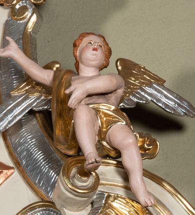 Zdjęcie nr 12: Nastawa ołtarzowa architektoniczna, jednoosiowa, jednokondygnacyjna ze zwieńczeniem. Ołtarz sarkofagowy, wklęsło-wypukły, na cokole, z mensą. Nastawa ujęta parą kolumn o kapitelach kompozytowych, ustawionych na cokołach, dźwigających belkowanie o falistej linii, wyłamane na ich osi, z przerwanym architrawem nad polem środkowym. Na belkowaniu fragmenty przerwanego, falistego przyczółka, dekorowanego rocaille'em, z siedzącymi puttami. Kondygnacja flankowana spływami wolutowymi zdobionymi rocaille'em, opadającymi na cokoły oraz uszami utworzonymi z esowato skręconego akantu. W polu środkowym wnęka w formie stojącego prostokąta zamkniętego łukiem półkolistym nadwieszonym z uskokiem, ujęta profilowaną ramą, z obrazem przedstawiającym św. Piotra i św. Pawła. Zwieńczenie w formie zbliżonej do trapezu, zamkniętego falistym fragmentem gzymsu, flankowane spływami wolutowymi dekorowanymi karbowaną wstęgą oraz rokokowymi kartuszami. W polu obraz św. Heleny w formie zbliżonej do trapezu o falistej linii boków, ujęty profilowaną ramą. Całość zakończona medalionem z monogramem IHS, w otoku z obłoków i dwóch uskrzydlonych główek anielskich, w glorii promienistej. Struktura polichromowana w kolorze beżowym, ze złoconymi kolumnami, ornamentyką i profilami, srebrzonymi detalami i laserowanymi ramami obrazów. 
