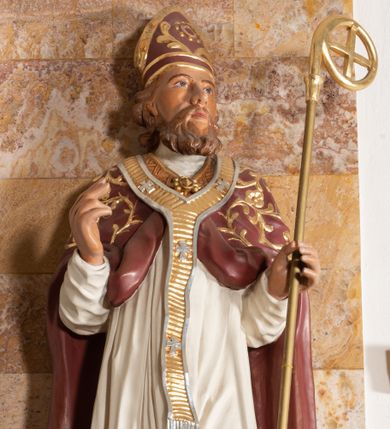 Zdjęcie nr 1: Rzeźba drążona z tyłu stoi na prostokątnej podstawie ustawionej na profilowanej, zwężającej się ku dołowi konsoli przyściennej. Postać biskupa jest ujęta frontalni w nieznacznym kontrapoście z głową lekko skierowaną w prawo. Prawą rękę Augustyn ma uniesioną przed siebie na wysokość piersi w lewej zaś trzyma pastorał o gładkiej, zamkniętej krzywaśni z wpisanym krzyżem równoramiennym. Święty ma pociągłą, wychudzoną twarz o szeroko otwartych oczach, mięsistym nosie i pełnych ustach. Głowę okala broda i lekko kręcone sięgające ramion włosy. Augustyn na głowie ma szkarłatną mitrę zdobiną złotą ornamentyką. Ubrany jest w sutannę, białą komże dekorowaną u spodu szeroką koronką oraz szkarłatną kapę pokrytą złocistym ornamentem i lamowaną złotą tasiemką. Na ramionach dodatkowo ma założony złocony i srebrzony paliusz. Na postumencie widoczny jest podpis: "Ś[WIĘTY] AUGUSTYN".