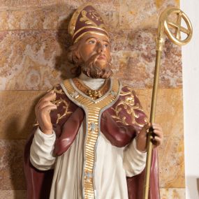 Zdjęcie nr 1: Rzeźba drążona z tyłu stoi na prostokątnej podstawie ustawionej na profilowanej, zwężającej się ku dołowi konsoli przyściennej. Postać biskupa jest ujęta frontalni w nieznacznym kontrapoście z głową lekko skierowaną w prawo. Prawą rękę Augustyn ma uniesioną przed siebie na wysokość piersi w lewej zaś trzyma pastorał o gładkiej, zamkniętej krzywaśni z wpisanym krzyżem równoramiennym. Święty ma pociągłą, wychudzoną twarz o szeroko otwartych oczach, mięsistym nosie i pełnych ustach. Głowę okala broda i lekko kręcone sięgające ramion włosy. Augustyn na głowie ma szkarłatną mitrę zdobiną złotą ornamentyką. Ubrany jest w sutannę, białą komże dekorowaną u spodu szeroką koronką oraz szkarłatną kapę pokrytą złocistym ornamentem i lamowaną złotą tasiemką. Na ramionach dodatkowo ma założony złocony i srebrzony paliusz. Na postumencie widoczny jest podpis: &quot;Ś[WIĘTY] AUGUSTYN&quot;.