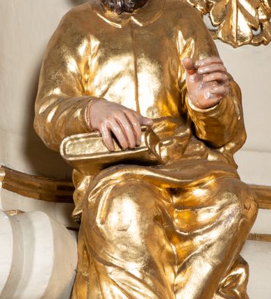 Zdjęcie nr 9: Ambona przyścienna, wisząca, z dostępem przez drzwi w partii zaplecka. Kosz na planie zbliżonym do koła o wklęsło-wypukłym zarysie, na cokole w postaci spłaszczonego wałka, z podwieszeniem w formie zbliżonej do spłaszczonej półkuli, zdobionej rozetami, ujętej lizenami dekorowanymi zwisami, zakończonej szyszką. Ścianki kosza wydzielone pilastrami dźwigającymi belkowanie tworzące parapet. Trzony dekorowane zwisami, ścianki rozetami. Na krawędzi cokołu siedzące figury czterech ewangelistów. Baldachim na planie analogicznym do kosza w formie belkowania z podwieszonym lambrekinem. Na nim woluty tworzące cokół dla wazonu, na którym znajduje się otwarta księga w glorii promienistej. Na księdze napis: „BŁOGOSŁA/WIENI / KTÓRZY / SŁUCHAIĄ / SŁOWA / BOŻEGO, I / STRZEGĄ / GO. / U S(więtego) Łukasza w rozdz(iale) XI wier(sz) [28]”. Na podniebieniu baldachimu gołębica Ducha Świętego w glorii promienistej. Struktura polichromowana w kolorze beżowym, ze złoconymi profilami, ornamentyką i detalami. 