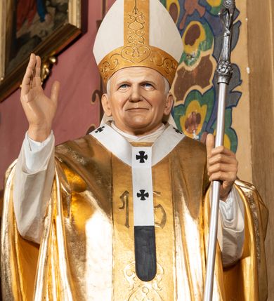 Zdjęcie nr 11: Ambona przyścienna, wisząca, z dostępem przez drzwi w partii zaplecka. Kosz na planie zbliżonym do koła o wklęsło-wypukłym zarysie, na cokole w postaci spłaszczonego wałka, z podwieszeniem w formie zbliżonej do spłaszczonej półkuli, zdobionej rozetami, ujętej lizenami dekorowanymi zwisami, zakończonej szyszką. Ścianki kosza wydzielone pilastrami dźwigającymi belkowanie tworzące parapet. Trzony dekorowane zwisami, ścianki rozetami. Na krawędzi cokołu siedzące figury czterech ewangelistów. Baldachim na planie analogicznym do kosza w formie belkowania z podwieszonym lambrekinem. Na nim woluty tworzące cokół dla wazonu, na którym znajduje się otwarta księga w glorii promienistej. Na księdze napis: „BŁOGOSŁA/WIENI / KTÓRZY / SŁUCHAIĄ / SŁOWA / BOŻEGO, I / STRZEGĄ / GO. / U S(więtego) Łukasza w rozdz(iale) XI wier(sz) [28]”. Na podniebieniu baldachimu gołębica Ducha Świętego w glorii promienistej. Struktura polichromowana w kolorze beżowym, ze złoconymi profilami, ornamentyką i detalami. 