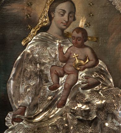 Zdjęcie nr 3: Obraz w formie stojącego prostokąta. W centrum na obłokach siedzi Maria, zwrócona w trzech czwartych w lewo, lewą ręką podtrzymuje Dzieciątko, w prawej, wyciągniętej w bok trzyma fragment płaszcza. Stopy opiera na sierpie księżyca, przesłoniętym metalowym, wokół którego wije się wąż. Maria ma owalną twarz, z wysokim czołem, o dużych, okrągłych oczach skierowanych w dół, dużym nosie i małych, pełnych ustach; okoloną długimi, brązowymi włosami. Wokół głowy ma wieniec z aplikowanych, metalowych gwiazd. Ubrana jest w strój przesłonięty metalową, srebrzoną sukienką w postaci sukni o kwiatowym wzorze, przepasaną w talii, na plecy ma narzucony płaszcz, zawinięty na jej lewym ramieniu, na którym siedzi Dzieciątko. Na głowie ma welon przesłonięty metalowym, złoconym. Jezus w pozycji siedzącej, zwrócony w trzech czwartych w prawo, w lewej dłoni trzyma jabłko królewskie, przesłonięte metalowym, złoconym, prawą unosi w geście błogosławieństwa. Twarz ma owalną, o okrągłych oczach skierowanych w dół, małym nosie i pełnych ustach, okoloną krótkimi, jasnobrązowymi włosami. Ciało ma nagie, pulchne. Od jego głowy odchodzą trzy wiązki aplikowanych, metalowych i złoconych promieni. Postacie ukazane są na tle gęstych, szaro-różowych obłoków, rozświetlonych na żółto w górnej części obrazu, wokół głowy Marii. W prawym górnym rogu dwie uskrzydlone główki anielskie z aplikowanmi metalowymi i srebrzonymi skrzydłami. 