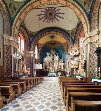 Zdjęcie nr 3: Kościół murowany, tynkowany, na kamiennym podmurowaniu, orientowany, jednonawowy. Prezbiterium prostokątne, krótkie, zamknięte trójbocznie, przy południowej ścianie prostokątna zakrystia z piętrem, z prostokątnym aneksem od zachodu. Nawa główna szersza od prezbiterium, na rzucie prostokąta, od zachodu przylega prostokątny przedsionek z wieżą na planie kwadratu. Wnętrze podzielone na cztery prostokątne przęsła i absydę, wydzielone arkadami, z gurtami spływającymi na zwielokrotnione pilastry. Każde przęsło nakryte sklepieniem o zaokrąglonych narożach. Łuk tęczowy półkolisty. W zachodniej części parapet chóru muzycznego wsparty na dwóch filarach i dwóch półfilarach, tworzących trzy arkady. Fasada trójosiowa, z wbudowaną wieżą, ujętą spłaszczonymi spływami zakończonymi cokołami z figurami. Osie wydzielone lizenami, podtrzymującymi profilowany gzyms, pod nim malowany fryz z dekoracją roślinną. Na osi portal w formie stojącego prostokąta zamkniętego łukiem odcinkowym, ujęty opaską tynkową, zakończoną kluczem. Drzwi drewniane, dwuskrzydłowe. Nad portalem fragment profilowanego gzymsu z daszkiem okapowym. Powyżej, na osi okno w formie stojącego prostokąta zamkniętego łukiem odcinkowym, w profilowanej opasce tynkowej, ujętej malowaną dekoracją geometryczną. Wieża dwukondygnacyjna, flankowana w narożach lizenami podtrzymującymi profilowany gzyms wieńczący. Na ścianie frontowej dwa okna na każdej kondygnacji, w formie stojącego prostokąta zamkniętego łukiem odcinkowym, w profilowanej opasce tynkowej, otoczonej malowaną dekoracją geometryczną, zwieńczone tarczą zegarową. Na pozostałych trzech ścianach wieży po jednym analogicznym oknie w drugiej kondygnacji i tarczy zegarowej. Elewacje północna i południowa artykułowane lizenami podtrzymującymi profilowany gzyms, z dekoracyjnym fryzem poniżej. Okna w formie stojącego prostokąta zamkniętego łukiem odcinkowym, w profilowanej opasce tynkowej z kluczem, ujętej malowaną dekoracją geometryczną: cztery w północnej i trzy w południowej. W zakrystii jedno prostokątne okno od południa i dwa w każdej kondygnacji od wschodu. Nawa główna i prezbiterium nakryte osobnymi dachami dwuspadowymi. Na ich połączeniu wieżyczka na sygnaturkę z latarnią, zwieńczona hełmem baniastym z krzyżem. Wieża nakryta hełmem baniastym zakończonym kulą z krzyżem. Zakrystia przykryta dachem trójspadowym, a aneks czterospadowym. 