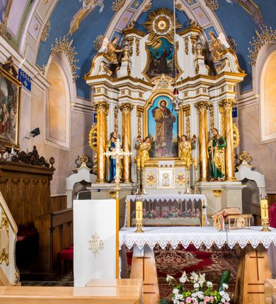 Zdjęcie nr 3: Ołtarz architektoniczny, jednokondygnacyjny, jednoosiowy, ze zwieńczeniem. Ołtarz murowany, prostopadłościenny z antepedium w formie prostokątnego obrazu ze sceną Ostatniej Wieczerzy według fresku Leonarda da Vinci. Na mensie tabernakulum w formie prostopadłościennej skrzyni osadzonej na niewielkim cokole i zwieńczonej gzymsem zdobionym wicią winnej latorośli. Metalowe drzwiczki w kształcie stojącego prostokąta z płyciną z motywem kielicha eucharystycznego, po bokach zdobione wicią winnej latorośli, flankowane parą prostokątnych płycin z motywami płaskorzeźbionych, uskrzydlonych główek anielskich. Na tabernakulum po bokach para figur klęczących aniołów w długich, złoconych sukniach. Retabulum osadzone na wysokim zryzalitowanym ukośnie po bokach cokole. Część środkowa ujęta dwoma parami kolumn ustawionych na tle dwóch par filarów, z czego skrajne bardziej wysunięte. Podpory wspierają wyłamujące się ponad nimi przerwane belkowanie. Zwieńczenie ujęte parą ukośnie ustawionych spływów wolutowych, zamknięte łukiem odcinkowym, flankowane przerwanym wolutowym przyczółkiem. Po bokach retabulum para bramek o przejściach zamkniętych łukami kotarowymi, zwieńczonych fragmentami gzymsów w postaci łuków wklęsło-wypukłych. Trzony filarów zdobione kampanulami, fryz rozetami. Retabulum ujmuje para ażurowych uszaków. Pośrodku przerwanego belkowania monogram maryjny. Pola spływów wolutowych zwieńczenia zdobią motywy kampanuli, szczyt w formie promienistej glorii z okiem Opatrzności pośrodku ujętym kręgiem obłoków. Na przerwanym przyczółku para figur siedzących aniołów w długich, złoconych sukniach. Pole części środkowej w kształcie stojącego prostokąta zamkniętego półkolistym łukiem nadwieszonym z uskokami, ujęte profilowaną, złoconą ramą. W środku obraz Matki Boskiej Pocieszenia, na zasuwie wizerunek św. Jakuba Starszego. Po bokach, między kolumnami para figur, po prawej stronie św. Paweł, po lewej św. Piotr. W zwieńczeniu obraz w kształcie trapezu o wklęsłych ramionach i podstawie, ściętych narożach dolnych, zamknięty łukiem wklęsło-wypukłym z przedstawieniem stygmatyzacji św. Franciszka. Struktura polichromowana w kolorze białym, częściowo marmoryzowana w odcieniach beżów, detal architektoniczny i ornamentyka złocone, marmoryzowane i srebrzone.     