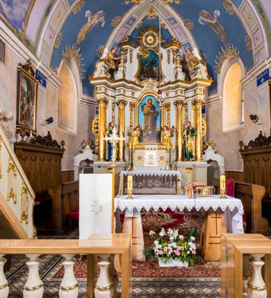 Zdjęcie nr 2: Ołtarz architektoniczny, jednokondygnacyjny, jednoosiowy, ze zwieńczeniem. Ołtarz murowany, prostopadłościenny z antepedium w formie prostokątnego obrazu ze sceną Ostatniej Wieczerzy według fresku Leonarda da Vinci. Na mensie tabernakulum w formie prostopadłościennej skrzyni osadzonej na niewielkim cokole i zwieńczonej gzymsem zdobionym wicią winnej latorośli. Metalowe drzwiczki w kształcie stojącego prostokąta z płyciną z motywem kielicha eucharystycznego, po bokach zdobione wicią winnej latorośli, flankowane parą prostokątnych płycin z motywami płaskorzeźbionych, uskrzydlonych główek anielskich. Na tabernakulum po bokach para figur klęczących aniołów w długich, złoconych sukniach. Retabulum osadzone na wysokim zryzalitowanym ukośnie po bokach cokole. Część środkowa ujęta dwoma parami kolumn ustawionych na tle dwóch par filarów, z czego skrajne bardziej wysunięte. Podpory wspierają wyłamujące się ponad nimi przerwane belkowanie. Zwieńczenie ujęte parą ukośnie ustawionych spływów wolutowych, zamknięte łukiem odcinkowym, flankowane przerwanym wolutowym przyczółkiem. Po bokach retabulum para bramek o przejściach zamkniętych łukami kotarowymi, zwieńczonych fragmentami gzymsów w postaci łuków wklęsło-wypukłych. Trzony filarów zdobione kampanulami, fryz rozetami. Retabulum ujmuje para ażurowych uszaków. Pośrodku przerwanego belkowania monogram maryjny. Pola spływów wolutowych zwieńczenia zdobią motywy kampanuli, szczyt w formie promienistej glorii z okiem Opatrzności pośrodku ujętym kręgiem obłoków. Na przerwanym przyczółku para figur siedzących aniołów w długich, złoconych sukniach. Pole części środkowej w kształcie stojącego prostokąta zamkniętego półkolistym łukiem nadwieszonym z uskokami, ujęte profilowaną, złoconą ramą. W środku obraz Matki Boskiej Pocieszenia, na zasuwie wizerunek św. Jakuba Starszego. Po bokach, między kolumnami para figur, po prawej stronie św. Paweł, po lewej św. Piotr. W zwieńczeniu obraz w kształcie trapezu o wklęsłych ramionach i podstawie, ściętych narożach dolnych, zamknięty łukiem wklęsło-wypukłym z przedstawieniem stygmatyzacji św. Franciszka. Struktura polichromowana w kolorze białym, częściowo marmoryzowana w odcieniach beżów, detal architektoniczny i ornamentyka złocone, marmoryzowane i srebrzone.     