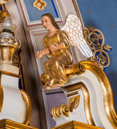 Zdjęcie nr 17: Ołtarz architektoniczny, jednokondygnacyjny, jednoosiowy, ze zwieńczeniem. Ołtarz murowany, prostopadłościenny z antepedium w formie prostokątnego obrazu ze sceną Ostatniej Wieczerzy według fresku Leonarda da Vinci. Na mensie tabernakulum w formie prostopadłościennej skrzyni osadzonej na niewielkim cokole i zwieńczonej gzymsem zdobionym wicią winnej latorośli. Metalowe drzwiczki w kształcie stojącego prostokąta z płyciną z motywem kielicha eucharystycznego, po bokach zdobione wicią winnej latorośli, flankowane parą prostokątnych płycin z motywami płaskorzeźbionych, uskrzydlonych główek anielskich. Na tabernakulum po bokach para figur klęczących aniołów w długich, złoconych sukniach. Retabulum osadzone na wysokim zryzalitowanym ukośnie po bokach cokole. Część środkowa ujęta dwoma parami kolumn ustawionych na tle dwóch par filarów, z czego skrajne bardziej wysunięte. Podpory wspierają wyłamujące się ponad nimi przerwane belkowanie. Zwieńczenie ujęte parą ukośnie ustawionych spływów wolutowych, zamknięte łukiem odcinkowym, flankowane przerwanym wolutowym przyczółkiem. Po bokach retabulum para bramek o przejściach zamkniętych łukami kotarowymi, zwieńczonych fragmentami gzymsów w postaci łuków wklęsło-wypukłych. Trzony filarów zdobione kampanulami, fryz rozetami. Retabulum ujmuje para ażurowych uszaków. Pośrodku przerwanego belkowania monogram maryjny. Pola spływów wolutowych zwieńczenia zdobią motywy kampanuli, szczyt w formie promienistej glorii z okiem Opatrzności pośrodku ujętym kręgiem obłoków. Na przerwanym przyczółku para figur siedzących aniołów w długich, złoconych sukniach. Pole części środkowej w kształcie stojącego prostokąta zamkniętego półkolistym łukiem nadwieszonym z uskokami, ujęte profilowaną, złoconą ramą. W środku obraz Matki Boskiej Pocieszenia, na zasuwie wizerunek św. Jakuba Starszego. Po bokach, między kolumnami para figur, po prawej stronie św. Paweł, po lewej św. Piotr. W zwieńczeniu obraz w kształcie trapezu o wklęsłych ramionach i podstawie, ściętych narożach dolnych, zamknięty łukiem wklęsło-wypukłym z przedstawieniem stygmatyzacji św. Franciszka. Struktura polichromowana w kolorze białym, częściowo marmoryzowana w odcieniach beżów, detal architektoniczny i ornamentyka złocone, marmoryzowane i srebrzone.     