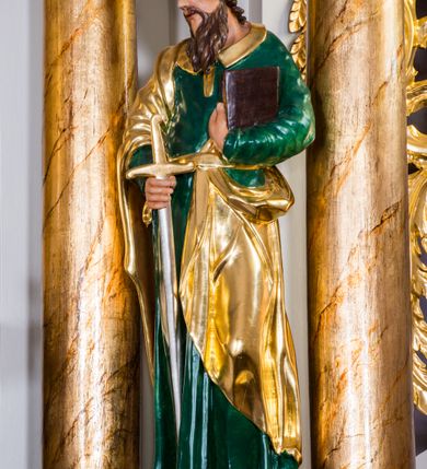 Zdjęcie nr 14: Ołtarz architektoniczny, jednokondygnacyjny, jednoosiowy, ze zwieńczeniem. Ołtarz murowany, prostopadłościenny z antepedium w formie prostokątnego obrazu ze sceną Ostatniej Wieczerzy według fresku Leonarda da Vinci. Na mensie tabernakulum w formie prostopadłościennej skrzyni osadzonej na niewielkim cokole i zwieńczonej gzymsem zdobionym wicią winnej latorośli. Metalowe drzwiczki w kształcie stojącego prostokąta z płyciną z motywem kielicha eucharystycznego, po bokach zdobione wicią winnej latorośli, flankowane parą prostokątnych płycin z motywami płaskorzeźbionych, uskrzydlonych główek anielskich. Na tabernakulum po bokach para figur klęczących aniołów w długich, złoconych sukniach. Retabulum osadzone na wysokim zryzalitowanym ukośnie po bokach cokole. Część środkowa ujęta dwoma parami kolumn ustawionych na tle dwóch par filarów, z czego skrajne bardziej wysunięte. Podpory wspierają wyłamujące się ponad nimi przerwane belkowanie. Zwieńczenie ujęte parą ukośnie ustawionych spływów wolutowych, zamknięte łukiem odcinkowym, flankowane przerwanym wolutowym przyczółkiem. Po bokach retabulum para bramek o przejściach zamkniętych łukami kotarowymi, zwieńczonych fragmentami gzymsów w postaci łuków wklęsło-wypukłych. Trzony filarów zdobione kampanulami, fryz rozetami. Retabulum ujmuje para ażurowych uszaków. Pośrodku przerwanego belkowania monogram maryjny. Pola spływów wolutowych zwieńczenia zdobią motywy kampanuli, szczyt w formie promienistej glorii z okiem Opatrzności pośrodku ujętym kręgiem obłoków. Na przerwanym przyczółku para figur siedzących aniołów w długich, złoconych sukniach. Pole części środkowej w kształcie stojącego prostokąta zamkniętego półkolistym łukiem nadwieszonym z uskokami, ujęte profilowaną, złoconą ramą. W środku obraz Matki Boskiej Pocieszenia, na zasuwie wizerunek św. Jakuba Starszego. Po bokach, między kolumnami para figur, po prawej stronie św. Paweł, po lewej św. Piotr. W zwieńczeniu obraz w kształcie trapezu o wklęsłych ramionach i podstawie, ściętych narożach dolnych, zamknięty łukiem wklęsło-wypukłym z przedstawieniem stygmatyzacji św. Franciszka. Struktura polichromowana w kolorze białym, częściowo marmoryzowana w odcieniach beżów, detal architektoniczny i ornamentyka złocone, marmoryzowane i srebrzone.     