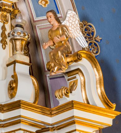 Zdjęcie nr 19: Ołtarz architektoniczny, jednokondygnacyjny, jednoosiowy, ze zwieńczeniem. Ołtarz murowany, prostopadłościenny z antepedium w formie prostokątnego obrazu ze sceną Ostatniej Wieczerzy według fresku Leonarda da Vinci. Na mensie tabernakulum w formie prostopadłościennej skrzyni osadzonej na niewielkim cokole i zwieńczonej gzymsem zdobionym wicią winnej latorośli. Metalowe drzwiczki w kształcie stojącego prostokąta z płyciną z motywem kielicha eucharystycznego, po bokach zdobione wicią winnej latorośli, flankowane parą prostokątnych płycin z motywami płaskorzeźbionych, uskrzydlonych główek anielskich. Na tabernakulum po bokach para figur klęczących aniołów w długich, złoconych sukniach. Retabulum osadzone na wysokim zryzalitowanym ukośnie po bokach cokole. Część środkowa ujęta dwoma parami kolumn ustawionych na tle dwóch par filarów, z czego skrajne bardziej wysunięte. Podpory wspierają wyłamujące się ponad nimi przerwane belkowanie. Zwieńczenie ujęte parą ukośnie ustawionych spływów wolutowych, zamknięte łukiem odcinkowym, flankowane przerwanym wolutowym przyczółkiem. Po bokach retabulum para bramek o przejściach zamkniętych łukami kotarowymi, zwieńczonych fragmentami gzymsów w postaci łuków wklęsło-wypukłych. Trzony filarów zdobione kampanulami, fryz rozetami. Retabulum ujmuje para ażurowych uszaków. Pośrodku przerwanego belkowania monogram maryjny. Pola spływów wolutowych zwieńczenia zdobią motywy kampanuli, szczyt w formie promienistej glorii z okiem Opatrzności pośrodku ujętym kręgiem obłoków. Na przerwanym przyczółku para figur siedzących aniołów w długich, złoconych sukniach. Pole części środkowej w kształcie stojącego prostokąta zamkniętego półkolistym łukiem nadwieszonym z uskokami, ujęte profilowaną, złoconą ramą. W środku obraz Matki Boskiej Pocieszenia, na zasuwie wizerunek św. Jakuba Starszego. Po bokach, między kolumnami para figur, po prawej stronie św. Paweł, po lewej św. Piotr. W zwieńczeniu obraz w kształcie trapezu o wklęsłych ramionach i podstawie, ściętych narożach dolnych, zamknięty łukiem wklęsło-wypukłym z przedstawieniem stygmatyzacji św. Franciszka. Struktura polichromowana w kolorze białym, częściowo marmoryzowana w odcieniach beżów, detal architektoniczny i ornamentyka złocone, marmoryzowane i srebrzone.     