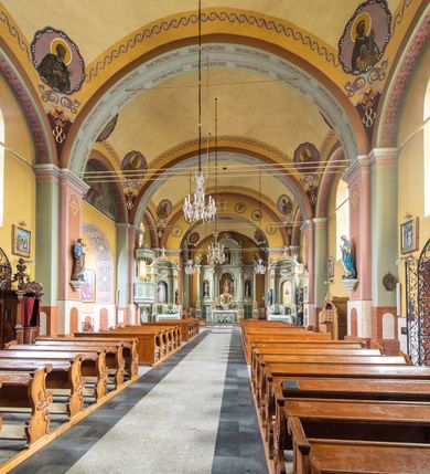 Zdjęcie nr 9: Orientowany kościół św. Urbana w Brzeszczach został wzniesiony w układzie czteroprzęsłowej nawy z prostokątnie zamkniętym prezbiterium, na przedłużeniu którego wzniesiono mniejszą, dwupiętrową zakrystię na rzucie prostokąta. Od północy i od południa do nawy dobudowano po jednej kaplicy, łącząc kaplicę południową z dawną zakrystią. Od zachodu do do nawy dostawiono masyw wieżowy z nieznacznie wysuniętą do przodu czworoboczną wieżę, flankowaną po bokach dwoma aneksami tej samej wysokości, co nawa. Kościół oraz dobudowane kaplice i zakrystia zostały przykryte miedzianymi dachami siodłowymi. Przy końcu nawy od wschodu na dachu nadwieszono wieżyczkę na sygnaturkę w formie latarni zwieńczonej baniastym hełmem. Podobną, bardziej przysadzistą wieżyczkę umieszczono na dachu kaplicy północnej. Elewacje zewnętrzne przeprute półokrągłymi oknami artykułowano za pomocą pilastrów o prostych głowicach wspartych na wysoki cokołach połączonych ze sobą gzymsem, podtrzymujących fazowane belkowanie przechodzące w profilowany gzyms koronujący. Elewacje wieży podzielona na dwie strefy rozdzielone belkowaniem wyłamanym w partii masywu wieżowego. Górna część wieży uzyskała ścięte naroża. W dolnej strefie w przyziemiu urządzono kruchtę, do której wejście na osi flankowane jest masywnym portalem utworzonym z dwóch czworobocznych podpór wspierających trójkątny przyczółek, ponad którym przepruto półokrągłe okno. Ponad gzymsem, w górnej strefie, zastosowano podział ramowy, ujmujący okulus, który pełni partię cokołową wspierającą flankujące górną część wieży pary pilastrów na każdej z czterech elewacji. Pilastry ustawione na postumentach o gładkich trzonach i kompozytowych głowicach wspierają fazowane belkowanie przechodzące w gzyms koronujący. Pomiędzy pilastrami przepruto półokrągłe okna z umieszczonymi nad nimi odcinkami belkowania. Ponad nimi zamontowano tarcze zegarowe. Wieżę zwieńczono baniastym hełmem z sześcioboczną latarnią nakrytą ostrosłupowym zwieńczeniem z krzyżem. Nawa główna otwiera się do kaplic bocznych za pomocą arkady. Wnętrze nakryto sklepieniem żaglastym. Całe wnętrze obiega marmurowa okładzina w formie boazerii. Chór muzyczny z prospektem organowym zajmuje całą szerokość nawy, wspierając się na dwóch filarach połączonych arkadą. Prosta balustrada chóru nad arkadą jest nieznacznie wypukła. W prezbiterium ustawiono ołtarz główny, a w kaplicach ołtarze boczne. Na ścianie północnej nawy przy prezbiterium zawieszono ambonę. 