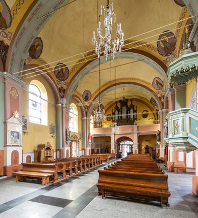 Zdjęcie nr 15: Orientowany kościół św. Urbana w Brzeszczach został wzniesiony w układzie czteroprzęsłowej nawy z prostokątnie zamkniętym prezbiterium, na przedłużeniu którego wzniesiono mniejszą, dwupiętrową zakrystię na rzucie prostokąta. Od północy i od południa do nawy dobudowano po jednej kaplicy, łącząc kaplicę południową z dawną zakrystią. Od zachodu do do nawy dostawiono masyw wieżowy z nieznacznie wysuniętą do przodu czworoboczną wieżę, flankowaną po bokach dwoma aneksami tej samej wysokości, co nawa. Kościół oraz dobudowane kaplice i zakrystia zostały przykryte miedzianymi dachami siodłowymi. Przy końcu nawy od wschodu na dachu nadwieszono wieżyczkę na sygnaturkę w formie latarni zwieńczonej baniastym hełmem. Podobną, bardziej przysadzistą wieżyczkę umieszczono na dachu kaplicy północnej. Elewacje zewnętrzne przeprute półokrągłymi oknami artykułowano za pomocą pilastrów o prostych głowicach wspartych na wysoki cokołach połączonych ze sobą gzymsem, podtrzymujących fazowane belkowanie przechodzące w profilowany gzyms koronujący. Elewacje wieży podzielona na dwie strefy rozdzielone belkowaniem wyłamanym w partii masywu wieżowego. Górna część wieży uzyskała ścięte naroża. W dolnej strefie w przyziemiu urządzono kruchtę, do której wejście na osi flankowane jest masywnym portalem utworzonym z dwóch czworobocznych podpór wspierających trójkątny przyczółek, ponad którym przepruto półokrągłe okno. Ponad gzymsem, w górnej strefie, zastosowano podział ramowy, ujmujący okulus, który pełni partię cokołową wspierającą flankujące górną część wieży pary pilastrów na każdej z czterech elewacji. Pilastry ustawione na postumentach o gładkich trzonach i kompozytowych głowicach wspierają fazowane belkowanie przechodzące w gzyms koronujący. Pomiędzy pilastrami przepruto półokrągłe okna z umieszczonymi nad nimi odcinkami belkowania. Ponad nimi zamontowano tarcze zegarowe. Wieżę zwieńczono baniastym hełmem z sześcioboczną latarnią nakrytą ostrosłupowym zwieńczeniem z krzyżem. Nawa główna otwiera się do kaplic bocznych za pomocą arkady. Wnętrze nakryto sklepieniem żaglastym. Całe wnętrze obiega marmurowa okładzina w formie boazerii. Chór muzyczny z prospektem organowym zajmuje całą szerokość nawy, wspierając się na dwóch filarach połączonych arkadą. Prosta balustrada chóru nad arkadą jest nieznacznie wypukła. W prezbiterium ustawiono ołtarz główny, a w kaplicach ołtarze boczne. Na ścianie północnej nawy przy prezbiterium zawieszono ambonę. 