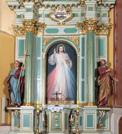 Zdjęcie nr 1: Ołtarz przyścienny, prostopadłościenny, z antepedium, na którym umieszczone są rzeźbione litery IHS; mensa drewniana z kamiennym portatylem. Na mensie znajduje się tabernakulum o kształcie graniastosłupa, z drzwiczkami ozdobionymi rzeźbionym kielichem z hostią. Nastawa ołtarzowa jest architektoniczna, jednoosiowa, jednokondygnacyjna ze zwieńczeniem. Osadzona na podwójnym postumencie, flankowana pilastrami o kompozytowych kapitelach i kanelowanymi kolumnami o kompozytowych kapitelach, które podtrzymują belkowanie. Ponad belkowaniem znajduje się przełamany przyczółek w formie łuku półkolistego, bogato profilowany, ozdobiony ulistnionymi konsolkami i rozetami oraz girlandami z owoców. W partii fryzu kartusz o fantazyjnym wykroju, ujęty wolutami i listkami akantu. Na belkowaniu siedzą po bokach nagie putta, odziane w opaski na biodrach, a pośrodku znajduje się krzyż osadzony na postumencie z liśćmi. Po obu stronach ołtarza na konsolach o krawędziach ozdobionych ornamentem małżowinowym stoją figury trudnych do identyfikacji świętych, być może apostołów. W centralnej części ołtarza wnęka prostokątna, zamknięta łukiem półkolistym. W niej obraz z przedstawieniem „Jezu ufam Tobie”. 