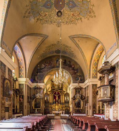 Zdjęcie nr 6: Kompleks klasztorny jest na rzucie czworoboku, z wirydarzem pośrodku i kościołem przylegającym od wschodu. Kościół, zwrócony w kierunku południowo-wschodnim, jest budowlą murowaną z cegły i kamienia, na rzucie podłużnym. Korpus jest jednonawowy i dwuprzęsłowy. Do dwuprzęsłowego prezbiterium na rzucie prostokąta od wschodu przylega zakrystia, do korpusu nawowego kaplica na rzucie ośmioboku z niewysoką przyległością, natomiast do fasady kruchta. Nawa i prezbiterium przekryte są sklepieniami kolebkowymi z lunetami wspartymi na masywnych półfilarach. Przestrzeń prezbiterium od korpusu nawowego oddziela półkolista arkada łuku tęczowego. Artykulację ścian na zewnątrz kościoła stanowią ujmujące okna duże, prostokątne płyciny. Korpus i prezbiterium obiega gzyms koronujący. Szczyt kościoła trójkątny, kruchty w formie nadwieszonego łuku z wycinka elipsy z wklęsłymi uskokami. Do wnętrza prowadzą dwa otwory drzwiowe po wschodniej i północnej stronie kruchty z parą prostokątnych, dwuskrzydłowych drzwi. W szczycie fasady płytka wnęka w kształcie stojącego prostokąta zamkniętego półkoliście z wizerunkiem Niepokalanego Poczęcia Najświętszej Marii Panny, ujęta trzema okrągłymi oknami. W szczycie kruchty analogiczna wnęka z figurą św. Floriana. Pośrodku fasady duże okno w kształcie stojącego prostokąta zamkniętego łukiem odcinkowym. Analogiczne okna w przęsłach korpusu i prezbiterium oraz na jego zamknięciu. Szczyt prezbiterium artykułuje płytka wnęka w kształcie stojącego prostokąta zamkniętego półkoliście z wizerunkiem św. Franciszka adorującego Jezusa na krzyżu flankowana parą okrągłych okien. Korpus i prezbiterium przekryte dachami dwuspadowymi, nad prezbiterium wieżyczka na sygnaturkę. Ściany kaplicy bocznej w formie półkolistych arkad, wypełnionych dużymi oknami z dekoracją maswerkową w górnej partii i przeszklonym otworem drzwiowym, zwieńczonych trójkątnymi szczytami. Ujmują je pary pilastrów, szczyty artykułuje fryz arkadkowy. Kaplicę wieńczy hełm pinaklowy z latarnią. Ściany sąsiedniej przyległości, nakrytej dachem pulpitowym i zakrystii z dachem trójspadowym, artykułuje fryz arkadkowy z lizenami. Tynki pomalowane są w odcieniach żółci. 