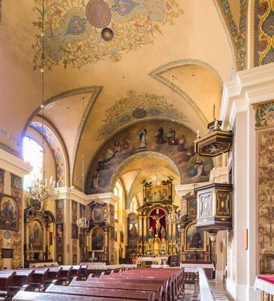 Zdjęcie nr 8: Kompleks klasztorny jest na rzucie czworoboku, z wirydarzem pośrodku i kościołem przylegającym od wschodu. Kościół, zwrócony w kierunku południowo-wschodnim, jest budowlą murowaną z cegły i kamienia, na rzucie podłużnym. Korpus jest jednonawowy i dwuprzęsłowy. Do dwuprzęsłowego prezbiterium na rzucie prostokąta od wschodu przylega zakrystia, do korpusu nawowego kaplica na rzucie ośmioboku z niewysoką przyległością, natomiast do fasady kruchta. Nawa i prezbiterium przekryte są sklepieniami kolebkowymi z lunetami wspartymi na masywnych półfilarach. Przestrzeń prezbiterium od korpusu nawowego oddziela półkolista arkada łuku tęczowego. Artykulację ścian na zewnątrz kościoła stanowią ujmujące okna duże, prostokątne płyciny. Korpus i prezbiterium obiega gzyms koronujący. Szczyt kościoła trójkątny, kruchty w formie nadwieszonego łuku z wycinka elipsy z wklęsłymi uskokami. Do wnętrza prowadzą dwa otwory drzwiowe po wschodniej i północnej stronie kruchty z parą prostokątnych, dwuskrzydłowych drzwi. W szczycie fasady płytka wnęka w kształcie stojącego prostokąta zamkniętego półkoliście z wizerunkiem Niepokalanego Poczęcia Najświętszej Marii Panny, ujęta trzema okrągłymi oknami. W szczycie kruchty analogiczna wnęka z figurą św. Floriana. Pośrodku fasady duże okno w kształcie stojącego prostokąta zamkniętego łukiem odcinkowym. Analogiczne okna w przęsłach korpusu i prezbiterium oraz na jego zamknięciu. Szczyt prezbiterium artykułuje płytka wnęka w kształcie stojącego prostokąta zamkniętego półkoliście z wizerunkiem św. Franciszka adorującego Jezusa na krzyżu flankowana parą okrągłych okien. Korpus i prezbiterium przekryte dachami dwuspadowymi, nad prezbiterium wieżyczka na sygnaturkę. Ściany kaplicy bocznej w formie półkolistych arkad, wypełnionych dużymi oknami z dekoracją maswerkową w górnej partii i przeszklonym otworem drzwiowym, zwieńczonych trójkątnymi szczytami. Ujmują je pary pilastrów, szczyty artykułuje fryz arkadkowy. Kaplicę wieńczy hełm pinaklowy z latarnią. Ściany sąsiedniej przyległości, nakrytej dachem pulpitowym i zakrystii z dachem trójspadowym, artykułuje fryz arkadkowy z lizenami. Tynki pomalowane są w odcieniach żółci. 