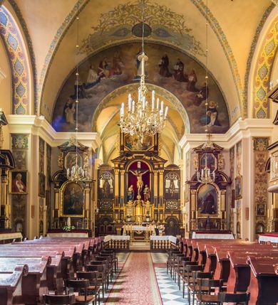 Zdjęcie nr 7: Kompleks klasztorny jest na rzucie czworoboku, z wirydarzem pośrodku i kościołem przylegającym od wschodu. Kościół, zwrócony w kierunku południowo-wschodnim, jest budowlą murowaną z cegły i kamienia, na rzucie podłużnym. Korpus jest jednonawowy i dwuprzęsłowy. Do dwuprzęsłowego prezbiterium na rzucie prostokąta od wschodu przylega zakrystia, do korpusu nawowego kaplica na rzucie ośmioboku z niewysoką przyległością, natomiast do fasady kruchta. Nawa i prezbiterium przekryte są sklepieniami kolebkowymi z lunetami wspartymi na masywnych półfilarach. Przestrzeń prezbiterium od korpusu nawowego oddziela półkolista arkada łuku tęczowego. Artykulację ścian na zewnątrz kościoła stanowią ujmujące okna duże, prostokątne płyciny. Korpus i prezbiterium obiega gzyms koronujący. Szczyt kościoła trójkątny, kruchty w formie nadwieszonego łuku z wycinka elipsy z wklęsłymi uskokami. Do wnętrza prowadzą dwa otwory drzwiowe po wschodniej i północnej stronie kruchty z parą prostokątnych, dwuskrzydłowych drzwi. W szczycie fasady płytka wnęka w kształcie stojącego prostokąta zamkniętego półkoliście z wizerunkiem Niepokalanego Poczęcia Najświętszej Marii Panny, ujęta trzema okrągłymi oknami. W szczycie kruchty analogiczna wnęka z figurą św. Floriana. Pośrodku fasady duże okno w kształcie stojącego prostokąta zamkniętego łukiem odcinkowym. Analogiczne okna w przęsłach korpusu i prezbiterium oraz na jego zamknięciu. Szczyt prezbiterium artykułuje płytka wnęka w kształcie stojącego prostokąta zamkniętego półkoliście z wizerunkiem św. Franciszka adorującego Jezusa na krzyżu flankowana parą okrągłych okien. Korpus i prezbiterium przekryte dachami dwuspadowymi, nad prezbiterium wieżyczka na sygnaturkę. Ściany kaplicy bocznej w formie półkolistych arkad, wypełnionych dużymi oknami z dekoracją maswerkową w górnej partii i przeszklonym otworem drzwiowym, zwieńczonych trójkątnymi szczytami. Ujmują je pary pilastrów, szczyty artykułuje fryz arkadkowy. Kaplicę wieńczy hełm pinaklowy z latarnią. Ściany sąsiedniej przyległości, nakrytej dachem pulpitowym i zakrystii z dachem trójspadowym, artykułuje fryz arkadkowy z lizenami. Tynki pomalowane są w odcieniach żółci. 