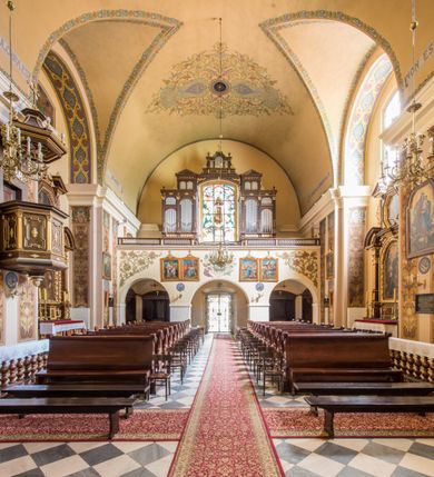 Zdjęcie nr 9: Kompleks klasztorny jest na rzucie czworoboku, z wirydarzem pośrodku i kościołem przylegającym od wschodu. Kościół, zwrócony w kierunku południowo-wschodnim, jest budowlą murowaną z cegły i kamienia, na rzucie podłużnym. Korpus jest jednonawowy i dwuprzęsłowy. Do dwuprzęsłowego prezbiterium na rzucie prostokąta od wschodu przylega zakrystia, do korpusu nawowego kaplica na rzucie ośmioboku z niewysoką przyległością, natomiast do fasady kruchta. Nawa i prezbiterium przekryte są sklepieniami kolebkowymi z lunetami wspartymi na masywnych półfilarach. Przestrzeń prezbiterium od korpusu nawowego oddziela półkolista arkada łuku tęczowego. Artykulację ścian na zewnątrz kościoła stanowią ujmujące okna duże, prostokątne płyciny. Korpus i prezbiterium obiega gzyms koronujący. Szczyt kościoła trójkątny, kruchty w formie nadwieszonego łuku z wycinka elipsy z wklęsłymi uskokami. Do wnętrza prowadzą dwa otwory drzwiowe po wschodniej i północnej stronie kruchty z parą prostokątnych, dwuskrzydłowych drzwi. W szczycie fasady płytka wnęka w kształcie stojącego prostokąta zamkniętego półkoliście z wizerunkiem Niepokalanego Poczęcia Najświętszej Marii Panny, ujęta trzema okrągłymi oknami. W szczycie kruchty analogiczna wnęka z figurą św. Floriana. Pośrodku fasady duże okno w kształcie stojącego prostokąta zamkniętego łukiem odcinkowym. Analogiczne okna w przęsłach korpusu i prezbiterium oraz na jego zamknięciu. Szczyt prezbiterium artykułuje płytka wnęka w kształcie stojącego prostokąta zamkniętego półkoliście z wizerunkiem św. Franciszka adorującego Jezusa na krzyżu flankowana parą okrągłych okien. Korpus i prezbiterium przekryte dachami dwuspadowymi, nad prezbiterium wieżyczka na sygnaturkę. Ściany kaplicy bocznej w formie półkolistych arkad, wypełnionych dużymi oknami z dekoracją maswerkową w górnej partii i przeszklonym otworem drzwiowym, zwieńczonych trójkątnymi szczytami. Ujmują je pary pilastrów, szczyty artykułuje fryz arkadkowy. Kaplicę wieńczy hełm pinaklowy z latarnią. Ściany sąsiedniej przyległości, nakrytej dachem pulpitowym i zakrystii z dachem trójspadowym, artykułuje fryz arkadkowy z lizenami. Tynki pomalowane są w odcieniach żółci. 