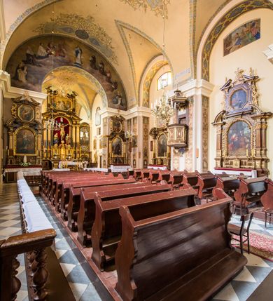 Zdjęcie nr 10: Kompleks klasztorny jest na rzucie czworoboku, z wirydarzem pośrodku i kościołem przylegającym od wschodu. Kościół, zwrócony w kierunku południowo-wschodnim, jest budowlą murowaną z cegły i kamienia, na rzucie podłużnym. Korpus jest jednonawowy i dwuprzęsłowy. Do dwuprzęsłowego prezbiterium na rzucie prostokąta od wschodu przylega zakrystia, do korpusu nawowego kaplica na rzucie ośmioboku z niewysoką przyległością, natomiast do fasady kruchta. Nawa i prezbiterium przekryte są sklepieniami kolebkowymi z lunetami wspartymi na masywnych półfilarach. Przestrzeń prezbiterium od korpusu nawowego oddziela półkolista arkada łuku tęczowego. Artykulację ścian na zewnątrz kościoła stanowią ujmujące okna duże, prostokątne płyciny. Korpus i prezbiterium obiega gzyms koronujący. Szczyt kościoła trójkątny, kruchty w formie nadwieszonego łuku z wycinka elipsy z wklęsłymi uskokami. Do wnętrza prowadzą dwa otwory drzwiowe po wschodniej i północnej stronie kruchty z parą prostokątnych, dwuskrzydłowych drzwi. W szczycie fasady płytka wnęka w kształcie stojącego prostokąta zamkniętego półkoliście z wizerunkiem Niepokalanego Poczęcia Najświętszej Marii Panny, ujęta trzema okrągłymi oknami. W szczycie kruchty analogiczna wnęka z figurą św. Floriana. Pośrodku fasady duże okno w kształcie stojącego prostokąta zamkniętego łukiem odcinkowym. Analogiczne okna w przęsłach korpusu i prezbiterium oraz na jego zamknięciu. Szczyt prezbiterium artykułuje płytka wnęka w kształcie stojącego prostokąta zamkniętego półkoliście z wizerunkiem św. Franciszka adorującego Jezusa na krzyżu flankowana parą okrągłych okien. Korpus i prezbiterium przekryte dachami dwuspadowymi, nad prezbiterium wieżyczka na sygnaturkę. Ściany kaplicy bocznej w formie półkolistych arkad, wypełnionych dużymi oknami z dekoracją maswerkową w górnej partii i przeszklonym otworem drzwiowym, zwieńczonych trójkątnymi szczytami. Ujmują je pary pilastrów, szczyty artykułuje fryz arkadkowy. Kaplicę wieńczy hełm pinaklowy z latarnią. Ściany sąsiedniej przyległości, nakrytej dachem pulpitowym i zakrystii z dachem trójspadowym, artykułuje fryz arkadkowy z lizenami. Tynki pomalowane są w odcieniach żółci. 