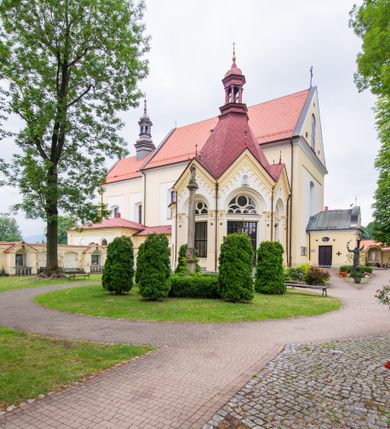 Zdjęcie nr 13: Kompleks klasztorny jest na rzucie czworoboku, z wirydarzem pośrodku i kościołem przylegającym od wschodu. Kościół, zwrócony w kierunku południowo-wschodnim, jest budowlą murowaną z cegły i kamienia, na rzucie podłużnym. Korpus jest jednonawowy i dwuprzęsłowy. Do dwuprzęsłowego prezbiterium na rzucie prostokąta od wschodu przylega zakrystia, do korpusu nawowego kaplica na rzucie ośmioboku z niewysoką przyległością, natomiast do fasady kruchta. Nawa i prezbiterium przekryte są sklepieniami kolebkowymi z lunetami wspartymi na masywnych półfilarach. Przestrzeń prezbiterium od korpusu nawowego oddziela półkolista arkada łuku tęczowego. Artykulację ścian na zewnątrz kościoła stanowią ujmujące okna duże, prostokątne płyciny. Korpus i prezbiterium obiega gzyms koronujący. Szczyt kościoła trójkątny, kruchty w formie nadwieszonego łuku z wycinka elipsy z wklęsłymi uskokami. Do wnętrza prowadzą dwa otwory drzwiowe po wschodniej i północnej stronie kruchty z parą prostokątnych, dwuskrzydłowych drzwi. W szczycie fasady płytka wnęka w kształcie stojącego prostokąta zamkniętego półkoliście z wizerunkiem Niepokalanego Poczęcia Najświętszej Marii Panny, ujęta trzema okrągłymi oknami. W szczycie kruchty analogiczna wnęka z figurą św. Floriana. Pośrodku fasady duże okno w kształcie stojącego prostokąta zamkniętego łukiem odcinkowym. Analogiczne okna w przęsłach korpusu i prezbiterium oraz na jego zamknięciu. Szczyt prezbiterium artykułuje płytka wnęka w kształcie stojącego prostokąta zamkniętego półkoliście z wizerunkiem św. Franciszka adorującego Jezusa na krzyżu flankowana parą okrągłych okien. Korpus i prezbiterium przekryte dachami dwuspadowymi, nad prezbiterium wieżyczka na sygnaturkę. Ściany kaplicy bocznej w formie półkolistych arkad, wypełnionych dużymi oknami z dekoracją maswerkową w górnej partii i przeszklonym otworem drzwiowym, zwieńczonych trójkątnymi szczytami. Ujmują je pary pilastrów, szczyty artykułuje fryz arkadkowy. Kaplicę wieńczy hełm pinaklowy z latarnią. Ściany sąsiedniej przyległości, nakrytej dachem pulpitowym i zakrystii z dachem trójspadowym, artykułuje fryz arkadkowy z lizenami. Tynki pomalowane są w odcieniach żółci. 