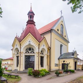 Zdjęcie nr 1: Kompleks klasztorny jest na rzucie czworoboku, z wirydarzem pośrodku i kościołem przylegającym od wschodu. Kościół, zwrócony w kierunku południowo-wschodnim, jest budowlą murowaną z cegły i kamienia, na rzucie podłużnym. Korpus jest jednonawowy i dwuprzęsłowy. Do dwuprzęsłowego prezbiterium na rzucie prostokąta od wschodu przylega zakrystia, do korpusu nawowego kaplica na rzucie ośmioboku z niewysoką przyległością, natomiast do fasady kruchta. Nawa i prezbiterium przekryte są sklepieniami kolebkowymi z lunetami wspartymi na masywnych półfilarach. Przestrzeń prezbiterium od korpusu nawowego oddziela półkolista arkada łuku tęczowego. Artykulację ścian na zewnątrz kościoła stanowią ujmujące okna duże, prostokątne płyciny. Korpus i prezbiterium obiega gzyms koronujący. Szczyt kościoła trójkątny, kruchty w formie nadwieszonego łuku z wycinka elipsy z wklęsłymi uskokami. Do wnętrza prowadzą dwa otwory drzwiowe po wschodniej i północnej stronie kruchty z parą prostokątnych, dwuskrzydłowych drzwi. W szczycie fasady płytka wnęka w kształcie stojącego prostokąta zamkniętego półkoliście z wizerunkiem Niepokalanego Poczęcia Najświętszej Marii Panny, ujęta trzema okrągłymi oknami. W szczycie kruchty analogiczna wnęka z figurą św. Floriana. Pośrodku fasady duże okno w kształcie stojącego prostokąta zamkniętego łukiem odcinkowym. Analogiczne okna w przęsłach korpusu i prezbiterium oraz na jego zamknięciu. Szczyt prezbiterium artykułuje płytka wnęka w kształcie stojącego prostokąta zamkniętego półkoliście z wizerunkiem św. Franciszka adorującego Jezusa na krzyżu flankowana parą okrągłych okien. Korpus i prezbiterium przekryte dachami dwuspadowymi, nad prezbiterium wieżyczka na sygnaturkę. Ściany kaplicy bocznej w formie półkolistych arkad, wypełnionych dużymi oknami z dekoracją maswerkową w górnej partii i przeszklonym otworem drzwiowym, zwieńczonych trójkątnymi szczytami. Ujmują je pary pilastrów, szczyty artykułuje fryz arkadkowy. Kaplicę wieńczy hełm pinaklowy z latarnią. Ściany sąsiedniej przyległości, nakrytej dachem pulpitowym i zakrystii z dachem trójspadowym, artykułuje fryz arkadkowy z lizenami. Tynki pomalowane są w odcieniach żółci. 
