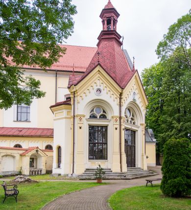 Zdjęcie nr 23: Kompleks klasztorny jest na rzucie czworoboku, z wirydarzem pośrodku i kościołem przylegającym od wschodu. Kościół, zwrócony w kierunku południowo-wschodnim, jest budowlą murowaną z cegły i kamienia, na rzucie podłużnym. Korpus jest jednonawowy i dwuprzęsłowy. Do dwuprzęsłowego prezbiterium na rzucie prostokąta od wschodu przylega zakrystia, do korpusu nawowego kaplica na rzucie ośmioboku z niewysoką przyległością, natomiast do fasady kruchta. Nawa i prezbiterium przekryte są sklepieniami kolebkowymi z lunetami wspartymi na masywnych półfilarach. Przestrzeń prezbiterium od korpusu nawowego oddziela półkolista arkada łuku tęczowego. Artykulację ścian na zewnątrz kościoła stanowią ujmujące okna duże, prostokątne płyciny. Korpus i prezbiterium obiega gzyms koronujący. Szczyt kościoła trójkątny, kruchty w formie nadwieszonego łuku z wycinka elipsy z wklęsłymi uskokami. Do wnętrza prowadzą dwa otwory drzwiowe po wschodniej i północnej stronie kruchty z parą prostokątnych, dwuskrzydłowych drzwi. W szczycie fasady płytka wnęka w kształcie stojącego prostokąta zamkniętego półkoliście z wizerunkiem Niepokalanego Poczęcia Najświętszej Marii Panny, ujęta trzema okrągłymi oknami. W szczycie kruchty analogiczna wnęka z figurą św. Floriana. Pośrodku fasady duże okno w kształcie stojącego prostokąta zamkniętego łukiem odcinkowym. Analogiczne okna w przęsłach korpusu i prezbiterium oraz na jego zamknięciu. Szczyt prezbiterium artykułuje płytka wnęka w kształcie stojącego prostokąta zamkniętego półkoliście z wizerunkiem św. Franciszka adorującego Jezusa na krzyżu flankowana parą okrągłych okien. Korpus i prezbiterium przekryte dachami dwuspadowymi, nad prezbiterium wieżyczka na sygnaturkę. Ściany kaplicy bocznej w formie półkolistych arkad, wypełnionych dużymi oknami z dekoracją maswerkową w górnej partii i przeszklonym otworem drzwiowym, zwieńczonych trójkątnymi szczytami. Ujmują je pary pilastrów, szczyty artykułuje fryz arkadkowy. Kaplicę wieńczy hełm pinaklowy z latarnią. Ściany sąsiedniej przyległości, nakrytej dachem pulpitowym i zakrystii z dachem trójspadowym, artykułuje fryz arkadkowy z lizenami. Tynki pomalowane są w odcieniach żółci. 