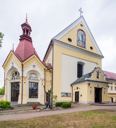 Zdjęcie nr 21: Kompleks klasztorny jest na rzucie czworoboku, z wirydarzem pośrodku i kościołem przylegającym od wschodu. Kościół, zwrócony w kierunku południowo-wschodnim, jest budowlą murowaną z cegły i kamienia, na rzucie podłużnym. Korpus jest jednonawowy i dwuprzęsłowy. Do dwuprzęsłowego prezbiterium na rzucie prostokąta od wschodu przylega zakrystia, do korpusu nawowego kaplica na rzucie ośmioboku z niewysoką przyległością, natomiast do fasady kruchta. Nawa i prezbiterium przekryte są sklepieniami kolebkowymi z lunetami wspartymi na masywnych półfilarach. Przestrzeń prezbiterium od korpusu nawowego oddziela półkolista arkada łuku tęczowego. Artykulację ścian na zewnątrz kościoła stanowią ujmujące okna duże, prostokątne płyciny. Korpus i prezbiterium obiega gzyms koronujący. Szczyt kościoła trójkątny, kruchty w formie nadwieszonego łuku z wycinka elipsy z wklęsłymi uskokami. Do wnętrza prowadzą dwa otwory drzwiowe po wschodniej i północnej stronie kruchty z parą prostokątnych, dwuskrzydłowych drzwi. W szczycie fasady płytka wnęka w kształcie stojącego prostokąta zamkniętego półkoliście z wizerunkiem Niepokalanego Poczęcia Najświętszej Marii Panny, ujęta trzema okrągłymi oknami. W szczycie kruchty analogiczna wnęka z figurą św. Floriana. Pośrodku fasady duże okno w kształcie stojącego prostokąta zamkniętego łukiem odcinkowym. Analogiczne okna w przęsłach korpusu i prezbiterium oraz na jego zamknięciu. Szczyt prezbiterium artykułuje płytka wnęka w kształcie stojącego prostokąta zamkniętego półkoliście z wizerunkiem św. Franciszka adorującego Jezusa na krzyżu flankowana parą okrągłych okien. Korpus i prezbiterium przekryte dachami dwuspadowymi, nad prezbiterium wieżyczka na sygnaturkę. Ściany kaplicy bocznej w formie półkolistych arkad, wypełnionych dużymi oknami z dekoracją maswerkową w górnej partii i przeszklonym otworem drzwiowym, zwieńczonych trójkątnymi szczytami. Ujmują je pary pilastrów, szczyty artykułuje fryz arkadkowy. Kaplicę wieńczy hełm pinaklowy z latarnią. Ściany sąsiedniej przyległości, nakrytej dachem pulpitowym i zakrystii z dachem trójspadowym, artykułuje fryz arkadkowy z lizenami. Tynki pomalowane są w odcieniach żółci. 