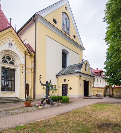 Zdjęcie nr 22: Kompleks klasztorny jest na rzucie czworoboku, z wirydarzem pośrodku i kościołem przylegającym od wschodu. Kościół, zwrócony w kierunku południowo-wschodnim, jest budowlą murowaną z cegły i kamienia, na rzucie podłużnym. Korpus jest jednonawowy i dwuprzęsłowy. Do dwuprzęsłowego prezbiterium na rzucie prostokąta od wschodu przylega zakrystia, do korpusu nawowego kaplica na rzucie ośmioboku z niewysoką przyległością, natomiast do fasady kruchta. Nawa i prezbiterium przekryte są sklepieniami kolebkowymi z lunetami wspartymi na masywnych półfilarach. Przestrzeń prezbiterium od korpusu nawowego oddziela półkolista arkada łuku tęczowego. Artykulację ścian na zewnątrz kościoła stanowią ujmujące okna duże, prostokątne płyciny. Korpus i prezbiterium obiega gzyms koronujący. Szczyt kościoła trójkątny, kruchty w formie nadwieszonego łuku z wycinka elipsy z wklęsłymi uskokami. Do wnętrza prowadzą dwa otwory drzwiowe po wschodniej i północnej stronie kruchty z parą prostokątnych, dwuskrzydłowych drzwi. W szczycie fasady płytka wnęka w kształcie stojącego prostokąta zamkniętego półkoliście z wizerunkiem Niepokalanego Poczęcia Najświętszej Marii Panny, ujęta trzema okrągłymi oknami. W szczycie kruchty analogiczna wnęka z figurą św. Floriana. Pośrodku fasady duże okno w kształcie stojącego prostokąta zamkniętego łukiem odcinkowym. Analogiczne okna w przęsłach korpusu i prezbiterium oraz na jego zamknięciu. Szczyt prezbiterium artykułuje płytka wnęka w kształcie stojącego prostokąta zamkniętego półkoliście z wizerunkiem św. Franciszka adorującego Jezusa na krzyżu flankowana parą okrągłych okien. Korpus i prezbiterium przekryte dachami dwuspadowymi, nad prezbiterium wieżyczka na sygnaturkę. Ściany kaplicy bocznej w formie półkolistych arkad, wypełnionych dużymi oknami z dekoracją maswerkową w górnej partii i przeszklonym otworem drzwiowym, zwieńczonych trójkątnymi szczytami. Ujmują je pary pilastrów, szczyty artykułuje fryz arkadkowy. Kaplicę wieńczy hełm pinaklowy z latarnią. Ściany sąsiedniej przyległości, nakrytej dachem pulpitowym i zakrystii z dachem trójspadowym, artykułuje fryz arkadkowy z lizenami. Tynki pomalowane są w odcieniach żółci. 
