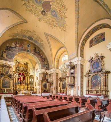 Zdjęcie nr 15: Kompleks klasztorny jest na rzucie czworoboku, z wirydarzem pośrodku i kościołem przylegającym od wschodu. Kościół, zwrócony w kierunku południowo-wschodnim, jest budowlą murowaną z cegły i kamienia, na rzucie podłużnym. Korpus jest jednonawowy i dwuprzęsłowy. Do dwuprzęsłowego prezbiterium na rzucie prostokąta od wschodu przylega zakrystia, do korpusu nawowego kaplica na rzucie ośmioboku z niewysoką przyległością, natomiast do fasady kruchta. Nawa i prezbiterium przekryte są sklepieniami kolebkowymi z lunetami wspartymi na masywnych półfilarach. Przestrzeń prezbiterium od korpusu nawowego oddziela półkolista arkada łuku tęczowego. Artykulację ścian na zewnątrz kościoła stanowią ujmujące okna duże, prostokątne płyciny. Korpus i prezbiterium obiega gzyms koronujący. Szczyt kościoła trójkątny, kruchty w formie nadwieszonego łuku z wycinka elipsy z wklęsłymi uskokami. Do wnętrza prowadzą dwa otwory drzwiowe po wschodniej i północnej stronie kruchty z parą prostokątnych, dwuskrzydłowych drzwi. W szczycie fasady płytka wnęka w kształcie stojącego prostokąta zamkniętego półkoliście z wizerunkiem Niepokalanego Poczęcia Najświętszej Marii Panny, ujęta trzema okrągłymi oknami. W szczycie kruchty analogiczna wnęka z figurą św. Floriana. Pośrodku fasady duże okno w kształcie stojącego prostokąta zamkniętego łukiem odcinkowym. Analogiczne okna w przęsłach korpusu i prezbiterium oraz na jego zamknięciu. Szczyt prezbiterium artykułuje płytka wnęka w kształcie stojącego prostokąta zamkniętego półkoliście z wizerunkiem św. Franciszka adorującego Jezusa na krzyżu flankowana parą okrągłych okien. Korpus i prezbiterium przekryte dachami dwuspadowymi, nad prezbiterium wieżyczka na sygnaturkę. Ściany kaplicy bocznej w formie półkolistych arkad, wypełnionych dużymi oknami z dekoracją maswerkową w górnej partii i przeszklonym otworem drzwiowym, zwieńczonych trójkątnymi szczytami. Ujmują je pary pilastrów, szczyty artykułuje fryz arkadkowy. Kaplicę wieńczy hełm pinaklowy z latarnią. Ściany sąsiedniej przyległości, nakrytej dachem pulpitowym i zakrystii z dachem trójspadowym, artykułuje fryz arkadkowy z lizenami. Tynki pomalowane są w odcieniach żółci. 