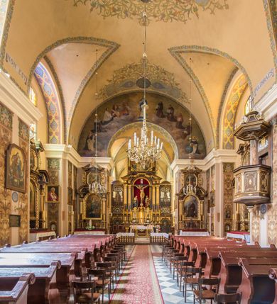 Zdjęcie nr 16: Kompleks klasztorny jest na rzucie czworoboku, z wirydarzem pośrodku i kościołem przylegającym od wschodu. Kościół, zwrócony w kierunku południowo-wschodnim, jest budowlą murowaną z cegły i kamienia, na rzucie podłużnym. Korpus jest jednonawowy i dwuprzęsłowy. Do dwuprzęsłowego prezbiterium na rzucie prostokąta od wschodu przylega zakrystia, do korpusu nawowego kaplica na rzucie ośmioboku z niewysoką przyległością, natomiast do fasady kruchta. Nawa i prezbiterium przekryte są sklepieniami kolebkowymi z lunetami wspartymi na masywnych półfilarach. Przestrzeń prezbiterium od korpusu nawowego oddziela półkolista arkada łuku tęczowego. Artykulację ścian na zewnątrz kościoła stanowią ujmujące okna duże, prostokątne płyciny. Korpus i prezbiterium obiega gzyms koronujący. Szczyt kościoła trójkątny, kruchty w formie nadwieszonego łuku z wycinka elipsy z wklęsłymi uskokami. Do wnętrza prowadzą dwa otwory drzwiowe po wschodniej i północnej stronie kruchty z parą prostokątnych, dwuskrzydłowych drzwi. W szczycie fasady płytka wnęka w kształcie stojącego prostokąta zamkniętego półkoliście z wizerunkiem Niepokalanego Poczęcia Najświętszej Marii Panny, ujęta trzema okrągłymi oknami. W szczycie kruchty analogiczna wnęka z figurą św. Floriana. Pośrodku fasady duże okno w kształcie stojącego prostokąta zamkniętego łukiem odcinkowym. Analogiczne okna w przęsłach korpusu i prezbiterium oraz na jego zamknięciu. Szczyt prezbiterium artykułuje płytka wnęka w kształcie stojącego prostokąta zamkniętego półkoliście z wizerunkiem św. Franciszka adorującego Jezusa na krzyżu flankowana parą okrągłych okien. Korpus i prezbiterium przekryte dachami dwuspadowymi, nad prezbiterium wieżyczka na sygnaturkę. Ściany kaplicy bocznej w formie półkolistych arkad, wypełnionych dużymi oknami z dekoracją maswerkową w górnej partii i przeszklonym otworem drzwiowym, zwieńczonych trójkątnymi szczytami. Ujmują je pary pilastrów, szczyty artykułuje fryz arkadkowy. Kaplicę wieńczy hełm pinaklowy z latarnią. Ściany sąsiedniej przyległości, nakrytej dachem pulpitowym i zakrystii z dachem trójspadowym, artykułuje fryz arkadkowy z lizenami. Tynki pomalowane są w odcieniach żółci. 