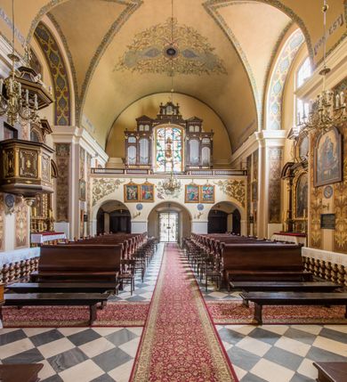 Zdjęcie nr 17: Kompleks klasztorny jest na rzucie czworoboku, z wirydarzem pośrodku i kościołem przylegającym od wschodu. Kościół, zwrócony w kierunku południowo-wschodnim, jest budowlą murowaną z cegły i kamienia, na rzucie podłużnym. Korpus jest jednonawowy i dwuprzęsłowy. Do dwuprzęsłowego prezbiterium na rzucie prostokąta od wschodu przylega zakrystia, do korpusu nawowego kaplica na rzucie ośmioboku z niewysoką przyległością, natomiast do fasady kruchta. Nawa i prezbiterium przekryte są sklepieniami kolebkowymi z lunetami wspartymi na masywnych półfilarach. Przestrzeń prezbiterium od korpusu nawowego oddziela półkolista arkada łuku tęczowego. Artykulację ścian na zewnątrz kościoła stanowią ujmujące okna duże, prostokątne płyciny. Korpus i prezbiterium obiega gzyms koronujący. Szczyt kościoła trójkątny, kruchty w formie nadwieszonego łuku z wycinka elipsy z wklęsłymi uskokami. Do wnętrza prowadzą dwa otwory drzwiowe po wschodniej i północnej stronie kruchty z parą prostokątnych, dwuskrzydłowych drzwi. W szczycie fasady płytka wnęka w kształcie stojącego prostokąta zamkniętego półkoliście z wizerunkiem Niepokalanego Poczęcia Najświętszej Marii Panny, ujęta trzema okrągłymi oknami. W szczycie kruchty analogiczna wnęka z figurą św. Floriana. Pośrodku fasady duże okno w kształcie stojącego prostokąta zamkniętego łukiem odcinkowym. Analogiczne okna w przęsłach korpusu i prezbiterium oraz na jego zamknięciu. Szczyt prezbiterium artykułuje płytka wnęka w kształcie stojącego prostokąta zamkniętego półkoliście z wizerunkiem św. Franciszka adorującego Jezusa na krzyżu flankowana parą okrągłych okien. Korpus i prezbiterium przekryte dachami dwuspadowymi, nad prezbiterium wieżyczka na sygnaturkę. Ściany kaplicy bocznej w formie półkolistych arkad, wypełnionych dużymi oknami z dekoracją maswerkową w górnej partii i przeszklonym otworem drzwiowym, zwieńczonych trójkątnymi szczytami. Ujmują je pary pilastrów, szczyty artykułuje fryz arkadkowy. Kaplicę wieńczy hełm pinaklowy z latarnią. Ściany sąsiedniej przyległości, nakrytej dachem pulpitowym i zakrystii z dachem trójspadowym, artykułuje fryz arkadkowy z lizenami. Tynki pomalowane są w odcieniach żółci. 