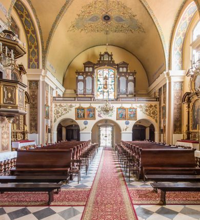 Zdjęcie nr 20: Kompleks klasztorny jest na rzucie czworoboku, z wirydarzem pośrodku i kościołem przylegającym od wschodu. Kościół, zwrócony w kierunku południowo-wschodnim, jest budowlą murowaną z cegły i kamienia, na rzucie podłużnym. Korpus jest jednonawowy i dwuprzęsłowy. Do dwuprzęsłowego prezbiterium na rzucie prostokąta od wschodu przylega zakrystia, do korpusu nawowego kaplica na rzucie ośmioboku z niewysoką przyległością, natomiast do fasady kruchta. Nawa i prezbiterium przekryte są sklepieniami kolebkowymi z lunetami wspartymi na masywnych półfilarach. Przestrzeń prezbiterium od korpusu nawowego oddziela półkolista arkada łuku tęczowego. Artykulację ścian na zewnątrz kościoła stanowią ujmujące okna duże, prostokątne płyciny. Korpus i prezbiterium obiega gzyms koronujący. Szczyt kościoła trójkątny, kruchty w formie nadwieszonego łuku z wycinka elipsy z wklęsłymi uskokami. Do wnętrza prowadzą dwa otwory drzwiowe po wschodniej i północnej stronie kruchty z parą prostokątnych, dwuskrzydłowych drzwi. W szczycie fasady płytka wnęka w kształcie stojącego prostokąta zamkniętego półkoliście z wizerunkiem Niepokalanego Poczęcia Najświętszej Marii Panny, ujęta trzema okrągłymi oknami. W szczycie kruchty analogiczna wnęka z figurą św. Floriana. Pośrodku fasady duże okno w kształcie stojącego prostokąta zamkniętego łukiem odcinkowym. Analogiczne okna w przęsłach korpusu i prezbiterium oraz na jego zamknięciu. Szczyt prezbiterium artykułuje płytka wnęka w kształcie stojącego prostokąta zamkniętego półkoliście z wizerunkiem św. Franciszka adorującego Jezusa na krzyżu flankowana parą okrągłych okien. Korpus i prezbiterium przekryte dachami dwuspadowymi, nad prezbiterium wieżyczka na sygnaturkę. Ściany kaplicy bocznej w formie półkolistych arkad, wypełnionych dużymi oknami z dekoracją maswerkową w górnej partii i przeszklonym otworem drzwiowym, zwieńczonych trójkątnymi szczytami. Ujmują je pary pilastrów, szczyty artykułuje fryz arkadkowy. Kaplicę wieńczy hełm pinaklowy z latarnią. Ściany sąsiedniej przyległości, nakrytej dachem pulpitowym i zakrystii z dachem trójspadowym, artykułuje fryz arkadkowy z lizenami. Tynki pomalowane są w odcieniach żółci. 