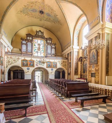 Zdjęcie nr 19: Kompleks klasztorny jest na rzucie czworoboku, z wirydarzem pośrodku i kościołem przylegającym od wschodu. Kościół, zwrócony w kierunku południowo-wschodnim, jest budowlą murowaną z cegły i kamienia, na rzucie podłużnym. Korpus jest jednonawowy i dwuprzęsłowy. Do dwuprzęsłowego prezbiterium na rzucie prostokąta od wschodu przylega zakrystia, do korpusu nawowego kaplica na rzucie ośmioboku z niewysoką przyległością, natomiast do fasady kruchta. Nawa i prezbiterium przekryte są sklepieniami kolebkowymi z lunetami wspartymi na masywnych półfilarach. Przestrzeń prezbiterium od korpusu nawowego oddziela półkolista arkada łuku tęczowego. Artykulację ścian na zewnątrz kościoła stanowią ujmujące okna duże, prostokątne płyciny. Korpus i prezbiterium obiega gzyms koronujący. Szczyt kościoła trójkątny, kruchty w formie nadwieszonego łuku z wycinka elipsy z wklęsłymi uskokami. Do wnętrza prowadzą dwa otwory drzwiowe po wschodniej i północnej stronie kruchty z parą prostokątnych, dwuskrzydłowych drzwi. W szczycie fasady płytka wnęka w kształcie stojącego prostokąta zamkniętego półkoliście z wizerunkiem Niepokalanego Poczęcia Najświętszej Marii Panny, ujęta trzema okrągłymi oknami. W szczycie kruchty analogiczna wnęka z figurą św. Floriana. Pośrodku fasady duże okno w kształcie stojącego prostokąta zamkniętego łukiem odcinkowym. Analogiczne okna w przęsłach korpusu i prezbiterium oraz na jego zamknięciu. Szczyt prezbiterium artykułuje płytka wnęka w kształcie stojącego prostokąta zamkniętego półkoliście z wizerunkiem św. Franciszka adorującego Jezusa na krzyżu flankowana parą okrągłych okien. Korpus i prezbiterium przekryte dachami dwuspadowymi, nad prezbiterium wieżyczka na sygnaturkę. Ściany kaplicy bocznej w formie półkolistych arkad, wypełnionych dużymi oknami z dekoracją maswerkową w górnej partii i przeszklonym otworem drzwiowym, zwieńczonych trójkątnymi szczytami. Ujmują je pary pilastrów, szczyty artykułuje fryz arkadkowy. Kaplicę wieńczy hełm pinaklowy z latarnią. Ściany sąsiedniej przyległości, nakrytej dachem pulpitowym i zakrystii z dachem trójspadowym, artykułuje fryz arkadkowy z lizenami. Tynki pomalowane są w odcieniach żółci. 