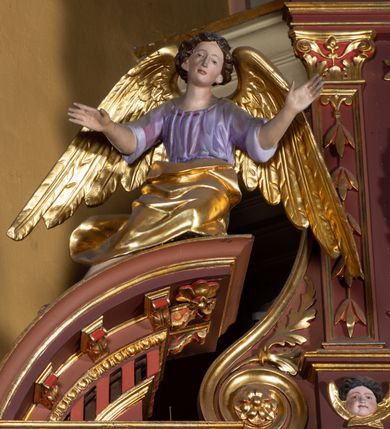 Zdjęcie nr 7: Ołtarz architektoniczny, jednoosiowy, jednokondygnacyjny, ze zwieńczeniem. Retabulum osadzone jest na wysokim, zdwojonym, zryzalitowanym uskokowo cokole. Ołtarz jest prostopadłościenny z drewnianą mensą. Pośrodku mensy znajduje się tabernakulum w formie prostopadłościennej szafki o lekko wypukłej przedniej ściance. Z przodu naroża ujmuje para półkolumienek, z tyłu półwałków. Prostokątne, zamknięte łukiem wklęsło-wypukłym drzwiczki zdobi polichromowane przedstawienie kielicha eucharystycznego na obłokach. Część środkową retabulum ujmuje para kolumn o żłobkowanych trzonach i korynckich kapitelach, ustawionych na tle zdwojonych pilastrów. Podpory dźwigają wyłamujące się ponad nimi belkowanie o silnie wysuniętym gzymsie. Zwieńczenie ma formę aediculi ujętej parą pilastrów i spływów wolutowych, zamkniętej trójkątnym przyczółkiem. Dodatkowo ujęta jest ona przerwanym, półkolistym przyczółkiem. Płycina antepedium jest w kształcie leżącego prostokąta z płaskorzeźbionym motywem złoconego, gorejącego serca, krzyża i kotwicy na tle srebrzonych obłoków ujętych promienistą glorią. Płyciny górnego cokołu (predelli) wypełnia stylizowana ornamentyka roślinna. Część środkową ujmuje para ażurowych uszaków z motywem kwiatu oraz wici akantu. U góry, pośrodku znajduje się uskrzydlona główka anielska. Powyżej, w partii belkowania, którego gzyms zdobi kostokowanie, umieszczony jest kartusz herbowy z monogramem maryjnym. Fryz zdobi stylizowana wić roślinna oraz para uskrzydlonych główek anielskich, natomiast zwieńczenie retabulum m.in. motywy roślinne, rozetki i kampanule. Szczyt tworzy podtrzymująca koronę para aniołów o sylwetkach od pasa w dół w formie liści akantu. Na przerwanym przyczółku znajduje się para przysiadających aniołów w sukniach w kolorze jasnofioletowym i pomarańczowym oraz złoconych płaszczach. Pole w części środkowej ma kształt stojącego prostokąta ujętego profilowaną, złoconą ramą. W środku znajduje się wizerunek Najświętszego Serca Jezusa. Pole w zwieńczeniu ma kształt stojącego owalu ujętego złoconą ramą w formie wieńca laurowego. Zawiera scenę Chrztu Jezusa w Jordanie. 
Struktura retabulum utrzymana jest w odcieniach brązu, partie detalu architektonicznego i ornamentyka są złocone. 
