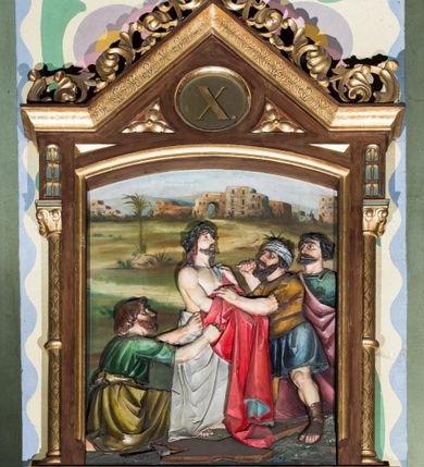 Zdjęcie nr 10: Czternaście płaskorzeźbionych stacji Drogi krzyżowej składa się z przedstawienia ujętego w taką samą architektoniczną, drewnianą ramę. Pole obrazowe uzyskał kształt stojącego prostokąta zamkniętego u góry łukiem odcinkowym. Flankują go smukłe półkolumienki wsparte na niskich bazach, ustawionych na prostokątnym, profilowanym cokole wspartym od dołu po bokach niewielkimi konsolami oraz udekorowanym podwieszonym na osi stylizowanym ornamentem roślinnym. Na cokole umieszczono podpis poszczególnej stacji. Kolumienki podtrzymują profilowane belkowanie w kształcie nadwieszonego trójkąta zwieńczonego krzyżem. Zewnętrze boki trójkąta zdobi ażurowy, złocony ornament roślinny. W polu trójkąta w medalionie wpisano kolejny numer stacji. Strukturę obramienia polichromowano na brązowo, natomiast kolumienki, wieńczące krzyże, ornamenty oraz profile zostały pozłocone. W polach obrazowych znalazły się wielopostaciowe, płaskorzeźbione kompozycje umieszczone najczęściej na tle pejzażu i architektury. Narracja każdego z obrazów skupia się na osobie Chrystusa, któremu towarzyszą inni ludzie, zgodnie z narracją kolejnej stacji. Przedstawione postacie wykonują gwałtowne i dynamiczne gesty. Na ich twarzach o jasnych karnacjach widoczne są różne emocje. Postacie ubrane są w obficie drapowane szaty o intensywnej i kontrastowej kolorystyce. Cykl przedstawia stacje z następującymi podpisami: I. Pan Jezus przez Piłata na śmierć skazany, II. Pan Jezus bierze krzyż na barki, III. Pan Jezus upada po raz pierwszy, IV. Pan Jezus spotyka się ze swoją Matką, V. Panu Jezusowi dopomaga Szymon Cyrenejczyk, VI. Panu Jezusowi ociera twarz św. Weronika, VII. Pan Jezus upada drugi raz, VIII. Pan Jezus pociesza płaczące niewiasty, IX. Pan Jezus upada po raz trzeci, X. Pan Jezus obnażony i żółcią napawany, XI. Pan Jezus do krzyża przybijany, XII. Pan Jezus umiera na krzyżu, XIII. Pan Jezus z krzyża zdjęty, XIV. Pan Jezus złożony w grobie. 