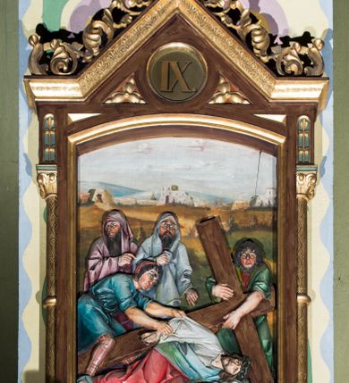 Zdjęcie nr 9: Czternaście płaskorzeźbionych stacji Drogi krzyżowej składa się z przedstawienia ujętego w taką samą architektoniczną, drewnianą ramę. Pole obrazowe uzyskał kształt stojącego prostokąta zamkniętego u góry łukiem odcinkowym. Flankują go smukłe półkolumienki wsparte na niskich bazach, ustawionych na prostokątnym, profilowanym cokole wspartym od dołu po bokach niewielkimi konsolami oraz udekorowanym podwieszonym na osi stylizowanym ornamentem roślinnym. Na cokole umieszczono podpis poszczególnej stacji. Kolumienki podtrzymują profilowane belkowanie w kształcie nadwieszonego trójkąta zwieńczonego krzyżem. Zewnętrze boki trójkąta zdobi ażurowy, złocony ornament roślinny. W polu trójkąta w medalionie wpisano kolejny numer stacji. Strukturę obramienia polichromowano na brązowo, natomiast kolumienki, wieńczące krzyże, ornamenty oraz profile zostały pozłocone. W polach obrazowych znalazły się wielopostaciowe, płaskorzeźbione kompozycje umieszczone najczęściej na tle pejzażu i architektury. Narracja każdego z obrazów skupia się na osobie Chrystusa, któremu towarzyszą inni ludzie, zgodnie z narracją kolejnej stacji. Przedstawione postacie wykonują gwałtowne i dynamiczne gesty. Na ich twarzach o jasnych karnacjach widoczne są różne emocje. Postacie ubrane są w obficie drapowane szaty o intensywnej i kontrastowej kolorystyce. Cykl przedstawia stacje z następującymi podpisami: I. Pan Jezus przez Piłata na śmierć skazany, II. Pan Jezus bierze krzyż na barki, III. Pan Jezus upada po raz pierwszy, IV. Pan Jezus spotyka się ze swoją Matką, V. Panu Jezusowi dopomaga Szymon Cyrenejczyk, VI. Panu Jezusowi ociera twarz św. Weronika, VII. Pan Jezus upada drugi raz, VIII. Pan Jezus pociesza płaczące niewiasty, IX. Pan Jezus upada po raz trzeci, X. Pan Jezus obnażony i żółcią napawany, XI. Pan Jezus do krzyża przybijany, XII. Pan Jezus umiera na krzyżu, XIII. Pan Jezus z krzyża zdjęty, XIV. Pan Jezus złożony w grobie. 