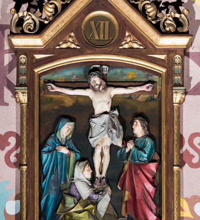 Zdjęcie nr 12: Czternaście płaskorzeźbionych stacji Drogi krzyżowej składa się z przedstawienia ujętego w taką samą architektoniczną, drewnianą ramę. Pole obrazowe uzyskał kształt stojącego prostokąta zamkniętego u góry łukiem odcinkowym. Flankują go smukłe półkolumienki wsparte na niskich bazach, ustawionych na prostokątnym, profilowanym cokole wspartym od dołu po bokach niewielkimi konsolami oraz udekorowanym podwieszonym na osi stylizowanym ornamentem roślinnym. Na cokole umieszczono podpis poszczególnej stacji. Kolumienki podtrzymują profilowane belkowanie w kształcie nadwieszonego trójkąta zwieńczonego krzyżem. Zewnętrze boki trójkąta zdobi ażurowy, złocony ornament roślinny. W polu trójkąta w medalionie wpisano kolejny numer stacji. Strukturę obramienia polichromowano na brązowo, natomiast kolumienki, wieńczące krzyże, ornamenty oraz profile zostały pozłocone. W polach obrazowych znalazły się wielopostaciowe, płaskorzeźbione kompozycje umieszczone najczęściej na tle pejzażu i architektury. Narracja każdego z obrazów skupia się na osobie Chrystusa, któremu towarzyszą inni ludzie, zgodnie z narracją kolejnej stacji. Przedstawione postacie wykonują gwałtowne i dynamiczne gesty. Na ich twarzach o jasnych karnacjach widoczne są różne emocje. Postacie ubrane są w obficie drapowane szaty o intensywnej i kontrastowej kolorystyce. Cykl przedstawia stacje z następującymi podpisami: I. Pan Jezus przez Piłata na śmierć skazany, II. Pan Jezus bierze krzyż na barki, III. Pan Jezus upada po raz pierwszy, IV. Pan Jezus spotyka się ze swoją Matką, V. Panu Jezusowi dopomaga Szymon Cyrenejczyk, VI. Panu Jezusowi ociera twarz św. Weronika, VII. Pan Jezus upada drugi raz, VIII. Pan Jezus pociesza płaczące niewiasty, IX. Pan Jezus upada po raz trzeci, X. Pan Jezus obnażony i żółcią napawany, XI. Pan Jezus do krzyża przybijany, XII. Pan Jezus umiera na krzyżu, XIII. Pan Jezus z krzyża zdjęty, XIV. Pan Jezus złożony w grobie. 