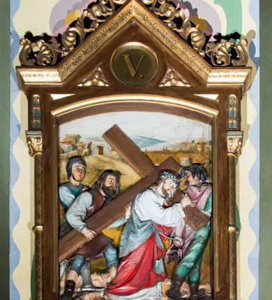 Zdjęcie nr 5: Czternaście płaskorzeźbionych stacji Drogi krzyżowej składa się z przedstawienia ujętego w taką samą architektoniczną, drewnianą ramę. Pole obrazowe uzyskał kształt stojącego prostokąta zamkniętego u góry łukiem odcinkowym. Flankują go smukłe półkolumienki wsparte na niskich bazach, ustawionych na prostokątnym, profilowanym cokole wspartym od dołu po bokach niewielkimi konsolami oraz udekorowanym podwieszonym na osi stylizowanym ornamentem roślinnym. Na cokole umieszczono podpis poszczególnej stacji. Kolumienki podtrzymują profilowane belkowanie w kształcie nadwieszonego trójkąta zwieńczonego krzyżem. Zewnętrze boki trójkąta zdobi ażurowy, złocony ornament roślinny. W polu trójkąta w medalionie wpisano kolejny numer stacji. Strukturę obramienia polichromowano na brązowo, natomiast kolumienki, wieńczące krzyże, ornamenty oraz profile zostały pozłocone. W polach obrazowych znalazły się wielopostaciowe, płaskorzeźbione kompozycje umieszczone najczęściej na tle pejzażu i architektury. Narracja każdego z obrazów skupia się na osobie Chrystusa, któremu towarzyszą inni ludzie, zgodnie z narracją kolejnej stacji. Przedstawione postacie wykonują gwałtowne i dynamiczne gesty. Na ich twarzach o jasnych karnacjach widoczne są różne emocje. Postacie ubrane są w obficie drapowane szaty o intensywnej i kontrastowej kolorystyce. Cykl przedstawia stacje z następującymi podpisami: I. Pan Jezus przez Piłata na śmierć skazany, II. Pan Jezus bierze krzyż na barki, III. Pan Jezus upada po raz pierwszy, IV. Pan Jezus spotyka się ze swoją Matką, V. Panu Jezusowi dopomaga Szymon Cyrenejczyk, VI. Panu Jezusowi ociera twarz św. Weronika, VII. Pan Jezus upada drugi raz, VIII. Pan Jezus pociesza płaczące niewiasty, IX. Pan Jezus upada po raz trzeci, X. Pan Jezus obnażony i żółcią napawany, XI. Pan Jezus do krzyża przybijany, XII. Pan Jezus umiera na krzyżu, XIII. Pan Jezus z krzyża zdjęty, XIV. Pan Jezus złożony w grobie. 