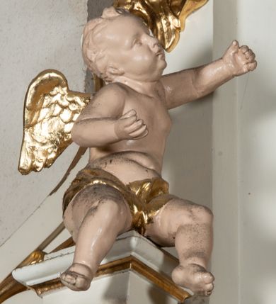 Zdjęcie nr 5: Ołtarz uzyskał formę architektonicznej struktury przyściennej, jednoosiowej, jednokondygnacyjnej ze zwieńczeniem. Marmurowy stipes ołtarzowy z mensą wykonano w formie prostopadłościanu dostawionego do wysokiego podwyższenia z marmuru ustawionego na podeście o ściętych narożach. Lico stipesu zdobi ryty symbol maryjny w otoku otoczonym przez stylizowane ramiona krzyża równoramiennego. Na podwyższeniu wsparto drewnianą strukturę nastawy ustawioną na cokole i flankowaną przez dwa filary. Przed lico kondygnacji wysunięto do przodu dwa postumenty, mające w pierwotnym zamyśle stanowić podpory dla flankujących strukturę dwóch kolumn podtrzymujący belkowanie wyłamane na ich osiach. Z kolumn zrezygnowano, a w ich miejsce w strukturę ołtarza oraz w trzony filarów zewnętrznych wprowadzono podłużne gabloty na wota. W polu kondygnacji wprowadzono prostokątną niszę zamkniętą półkoliście z mniejszym, czworobocznym obrazem Matki Boskiej Nieustającej Pomocy wiszącym na tle z szkarłatnej tkaniny. Poniżej obrazu umieszczono podłużną gablotę na wota. Ramę pola tworzą dwa pilastry o akantowych głowicach i trzonach dekorowanych zawieszonymi na taśmach bukiecikami kwiatów oraz półokrągły łuk, na którym umieszczono główki aniołków ze skrzyżowanymi skrzydełkami. Zwieńczenie utworzono z prostokątnego pola zamkniętego półkoliście ujętego obramieniem artykułowanym za pomocą rzędu kasetonów z rozetami, flankowanego przez dwa pilastry. W polu na niebieskim tle z tkaniny umieszczono ponad girlandą kwiatową w kształcie półksiężyca monogram maryjny także utworzony z girland roślino-kwiatowych. Zwieńczenie ujmuje para spływów wolutowych. Dwa pozostałe spływy wysunięte nad przedpolu zwieńczenia do przodu stanowią podstawę dla pary uskrzydlonych aniołków. Całość zwieńczenia zamyka kartusz prezentowany przez dwa aniołki oraz fantazyjny ornament spływający po jego bokach. W polu kartusza umieszczono napis: "O MARYJO / NIEUSTANNIE / WSPOMAGAJ / NAS". Struktura ołtarza polichromowana w kolorze kości słoniowej, profile i ornamenty zostały wyzłocone.  