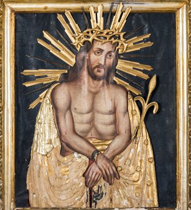 Zdjęcie nr 1: Obraz uzyskał kształt stojącego prostokąta ujętego złoconą, profilowaną ramą z dekoracją w typie wolich oczu. W centrum kompozycji ukazano na ciemnym tle frontalnie w dwóch trzecich Chrystusa z nieznacznie pochyloną głową w lewo ujętą w trzech czwartych. Zbawiciel ma skrzyżowane z przodu i związane sznurem ręce. W lewej dłoni trzyma wygiętą trzcinę. Jezus ma pociągłą twarz o jasnej karnacji okoloną krótką brodą i brązowymi włosami spływającymi na ramiona. Zbawiciel ma duży, prosty nos, wydatne usta i szeroko otwarte ciemne oczy. Na głowie ma złoconą koronę cierniową, spod której spływają krople krwi. Jego głowę otaczają ostre, złocone promienie. Krew widoczna jest także na odsłoniętym torsie oraz rękach. Zbawiciel ubrany jest w płaszcz narzucony na wątłe ramiona odsłaniający jego nagi tors. Zarówno płaszcz, jak i korona cierniowa, trzcina oraz sznur zostały przykryte płaskorzeźbioną, drewnianą sukienką wotywną. 