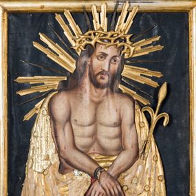 Zdjęcie nr 1: Obraz uzyskał kształt stojącego prostokąta ujętego złoconą, profilowaną ramą z dekoracją w typie wolich oczu. W centrum kompozycji ukazano na ciemnym tle frontalnie w dwóch trzecich Chrystusa z nieznacznie pochyloną głową w lewo ujętą w trzech czwartych. Zbawiciel ma skrzyżowane z przodu i związane sznurem ręce. W lewej dłoni trzyma wygiętą trzcinę. Jezus ma pociągłą twarz o jasnej karnacji okoloną krótką brodą i brązowymi włosami spływającymi na ramiona. Zbawiciel ma duży, prosty nos, wydatne usta i szeroko otwarte ciemne oczy. Na głowie ma złoconą koronę cierniową, spod której spływają krople krwi. Jego głowę otaczają ostre, złocone promienie. Krew widoczna jest także na odsłoniętym torsie oraz rękach. Zbawiciel ubrany jest w płaszcz narzucony na wątłe ramiona odsłaniający jego nagi tors. Zarówno płaszcz, jak i korona cierniowa, trzcina oraz sznur zostały przykryte płaskorzeźbioną, drewnianą sukienką wotywną. 